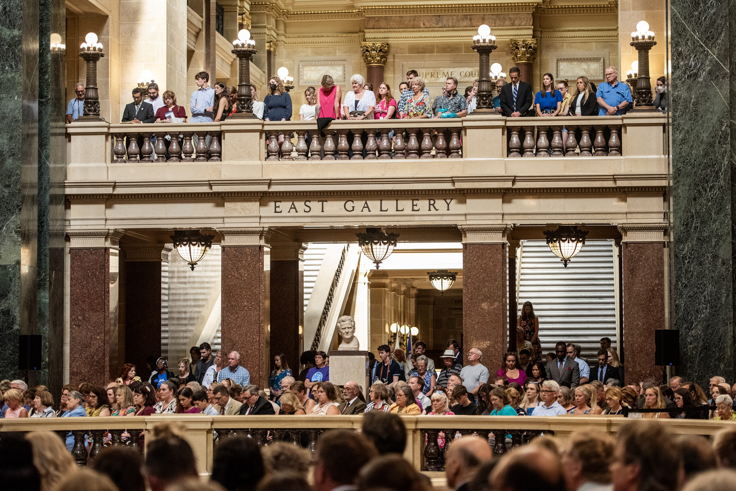 A crowd of people fill the East Gallery of the state capitol.
