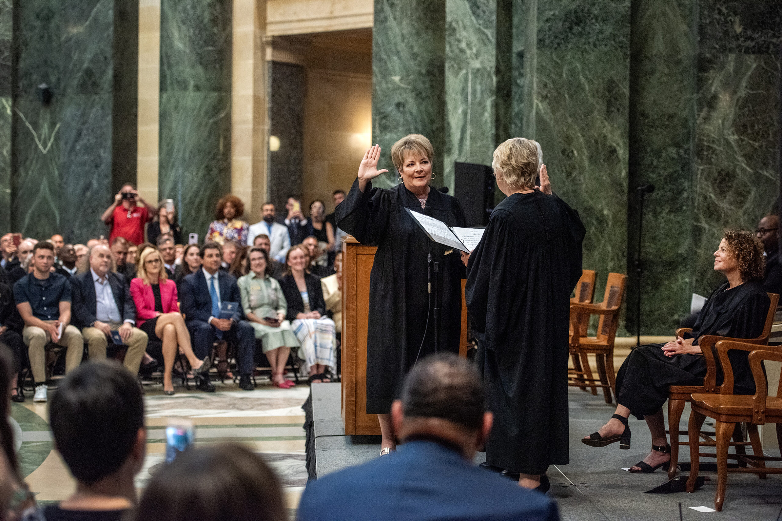 Janet Protasiewicz stands in front of a crowd as she swears in.