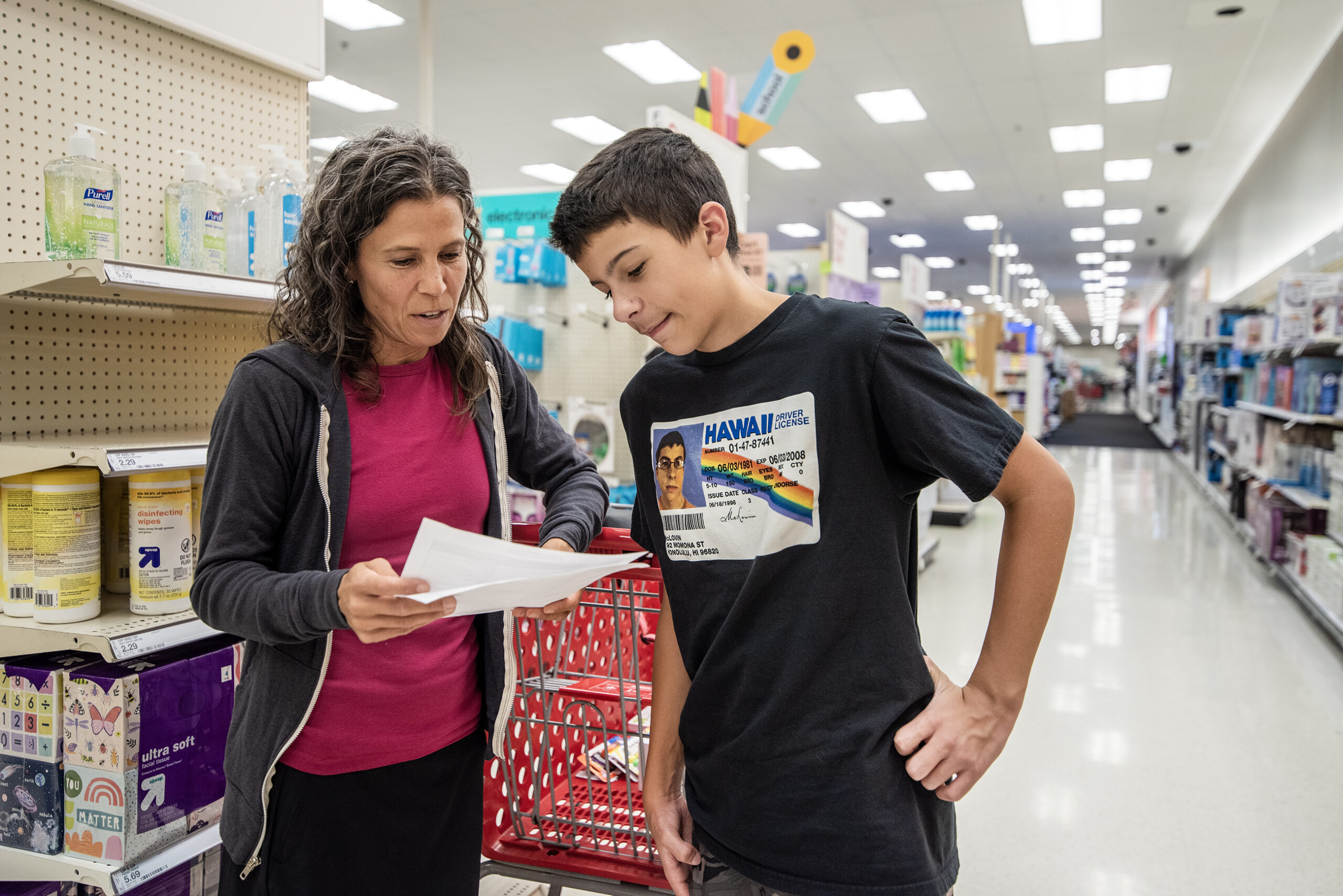 A mom and her son look at a school supply list in a store.