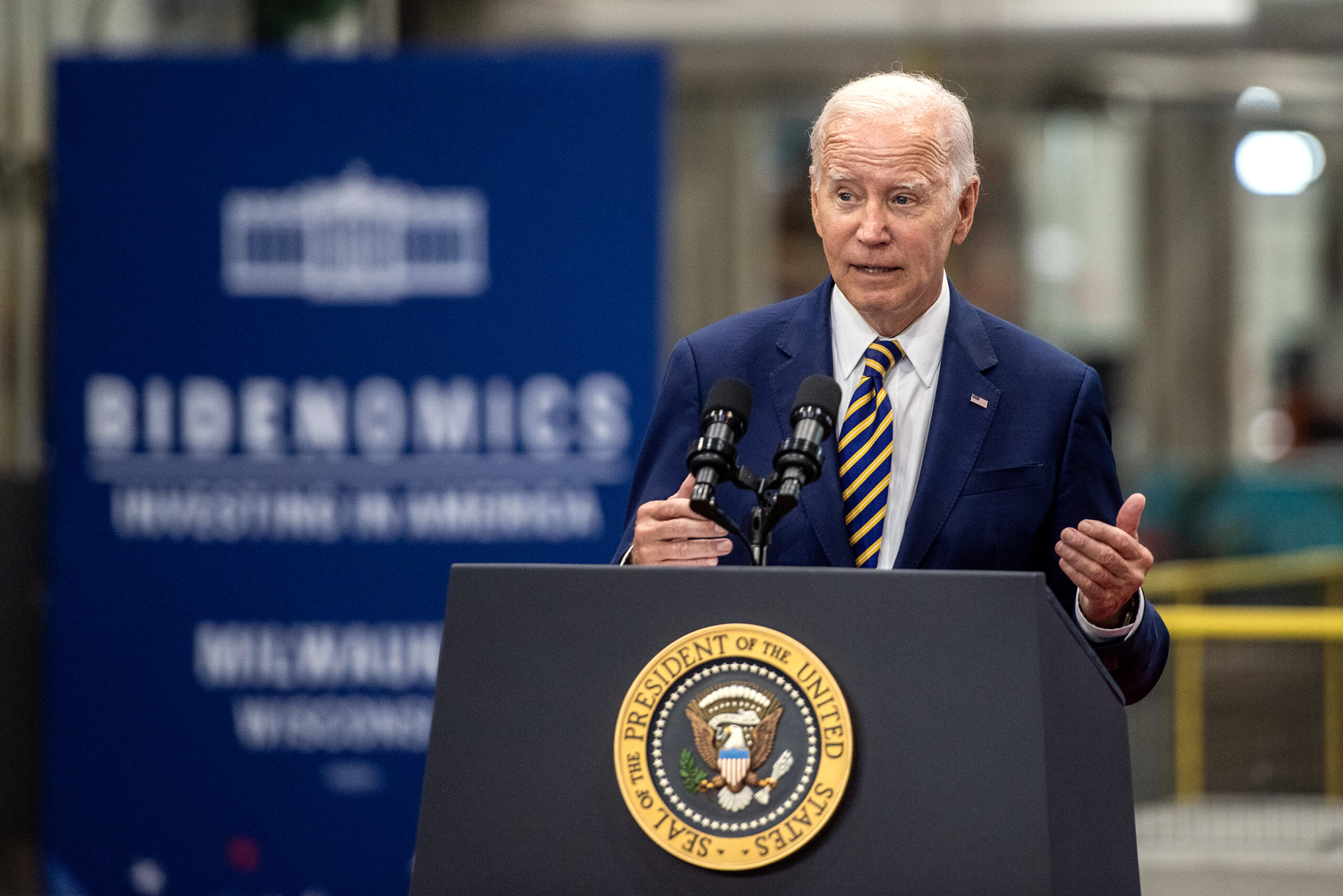 President Biden gestures as he speaks from behind a podium.