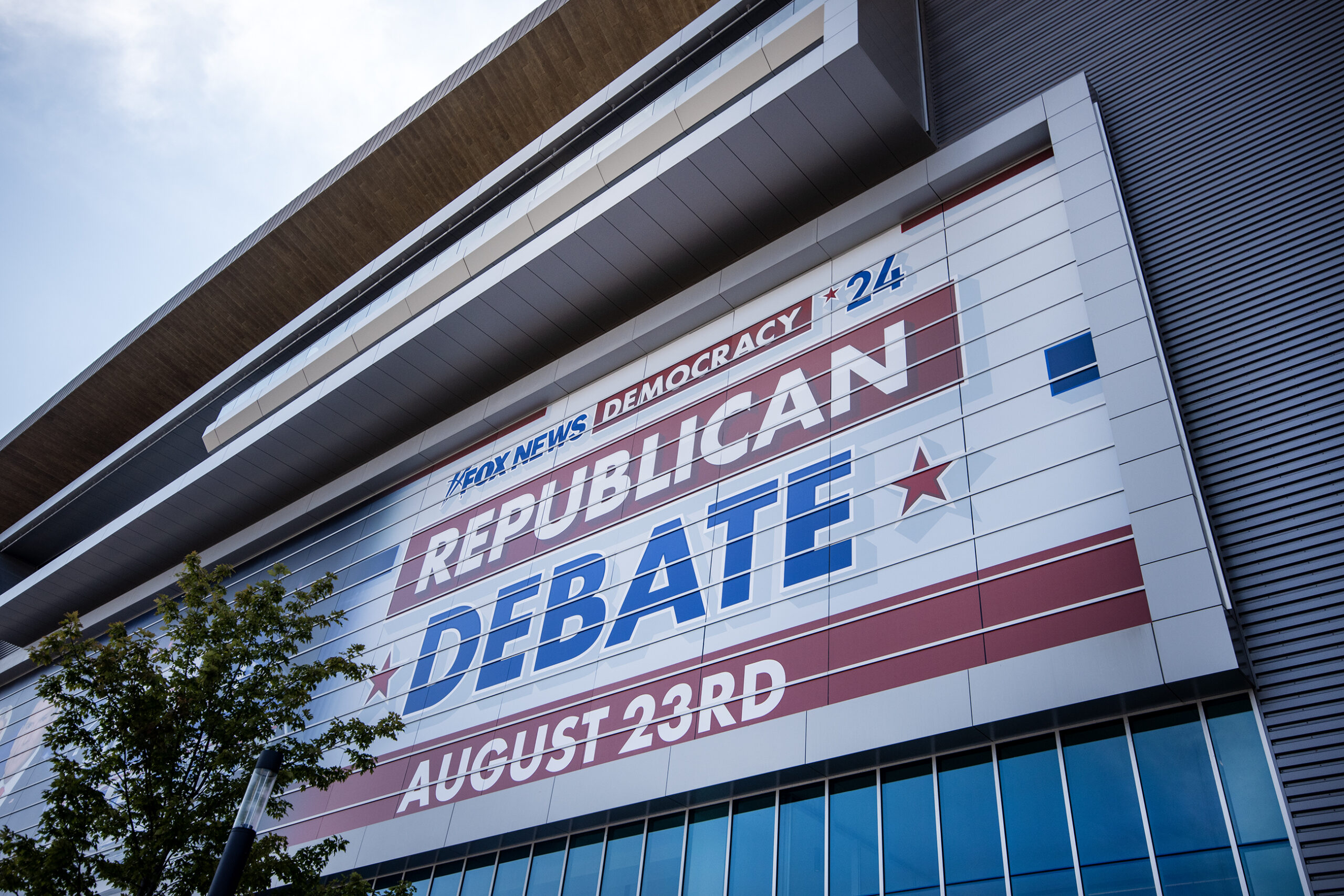A sign says "Republican Debate August 23rd" on the side of the Fiserv Forum.