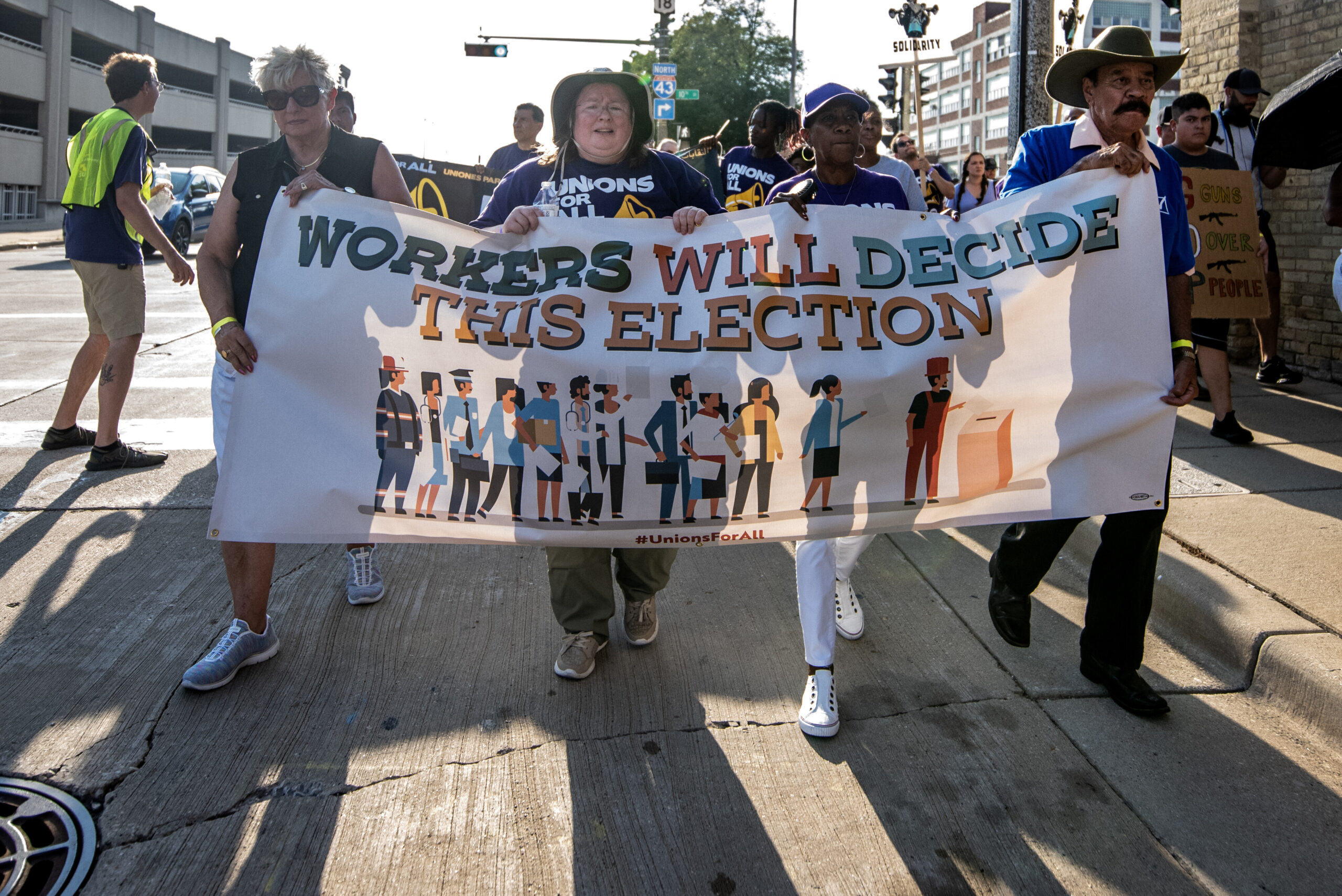 Four people hold a banner that says "Workers will decide this election."