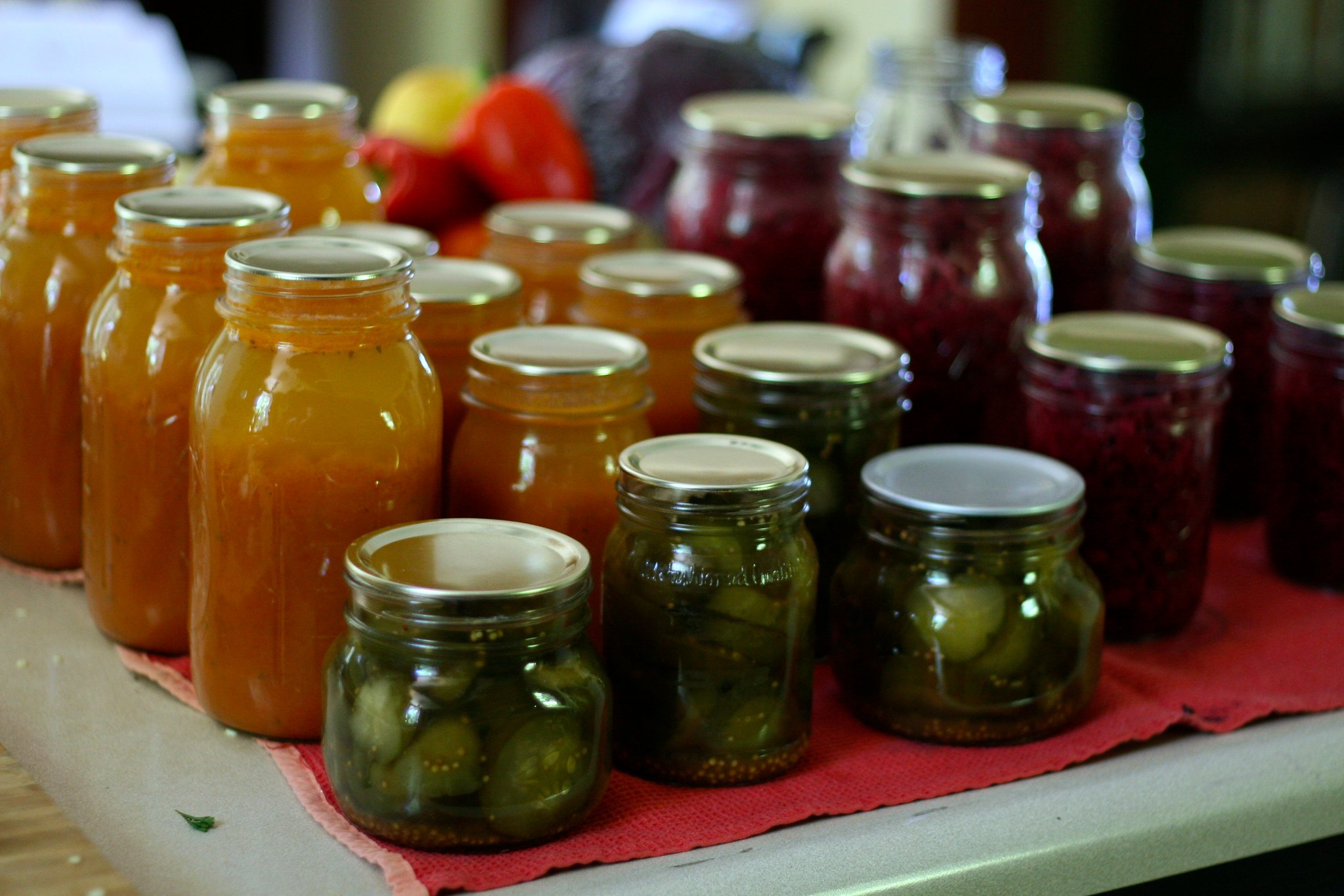 A counter lined with freshly canned jars of vegetables in small and large quart jars.