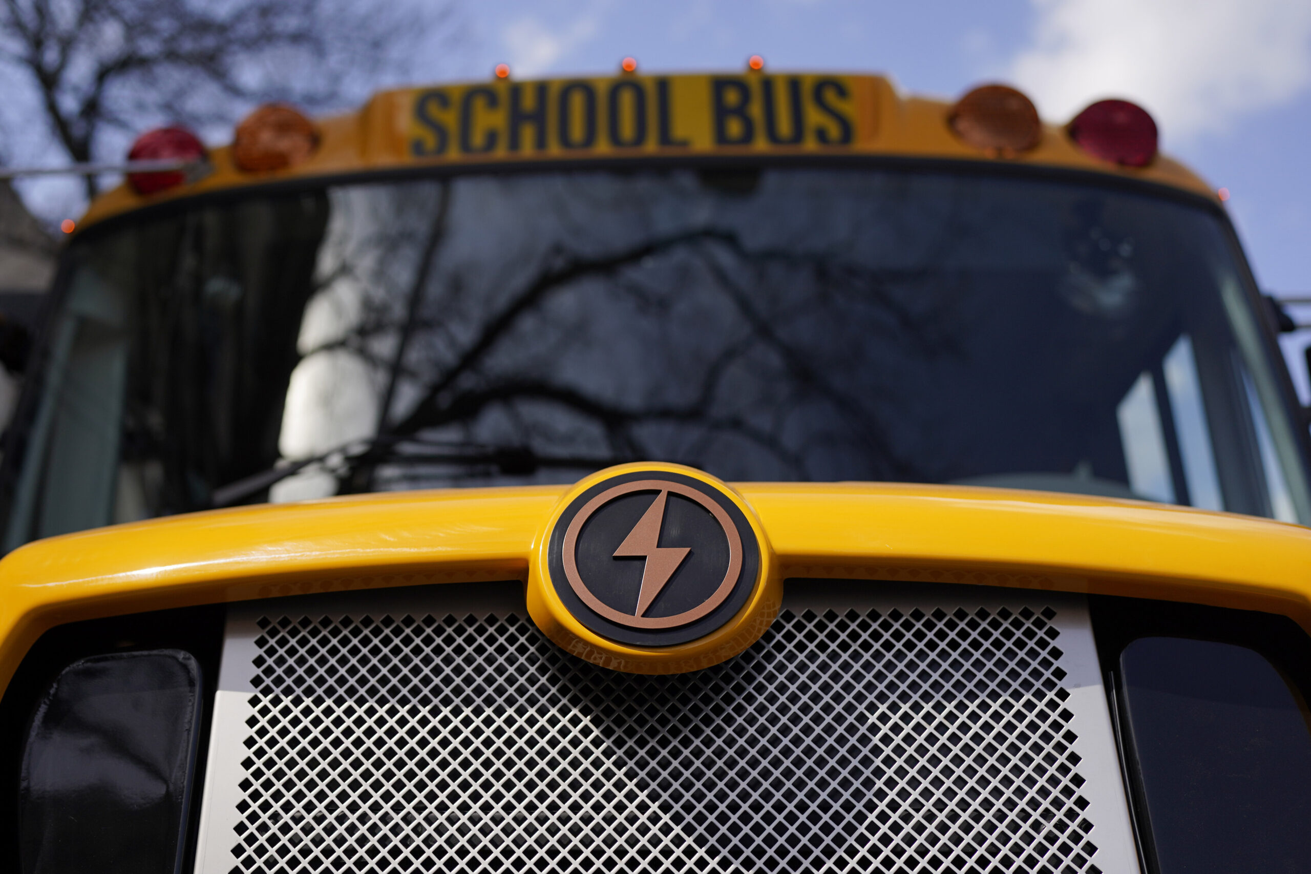 The front of an electric school bus is shown with its lightning bolt logo