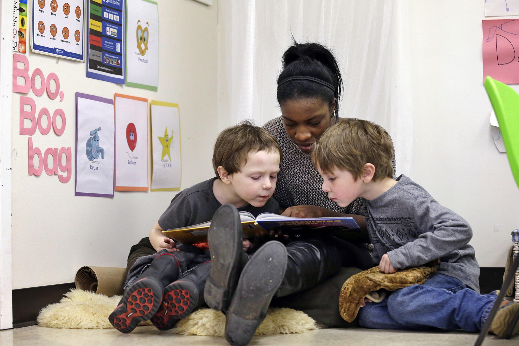 Assistant teacher D'onna Hartman reads to two young boys.