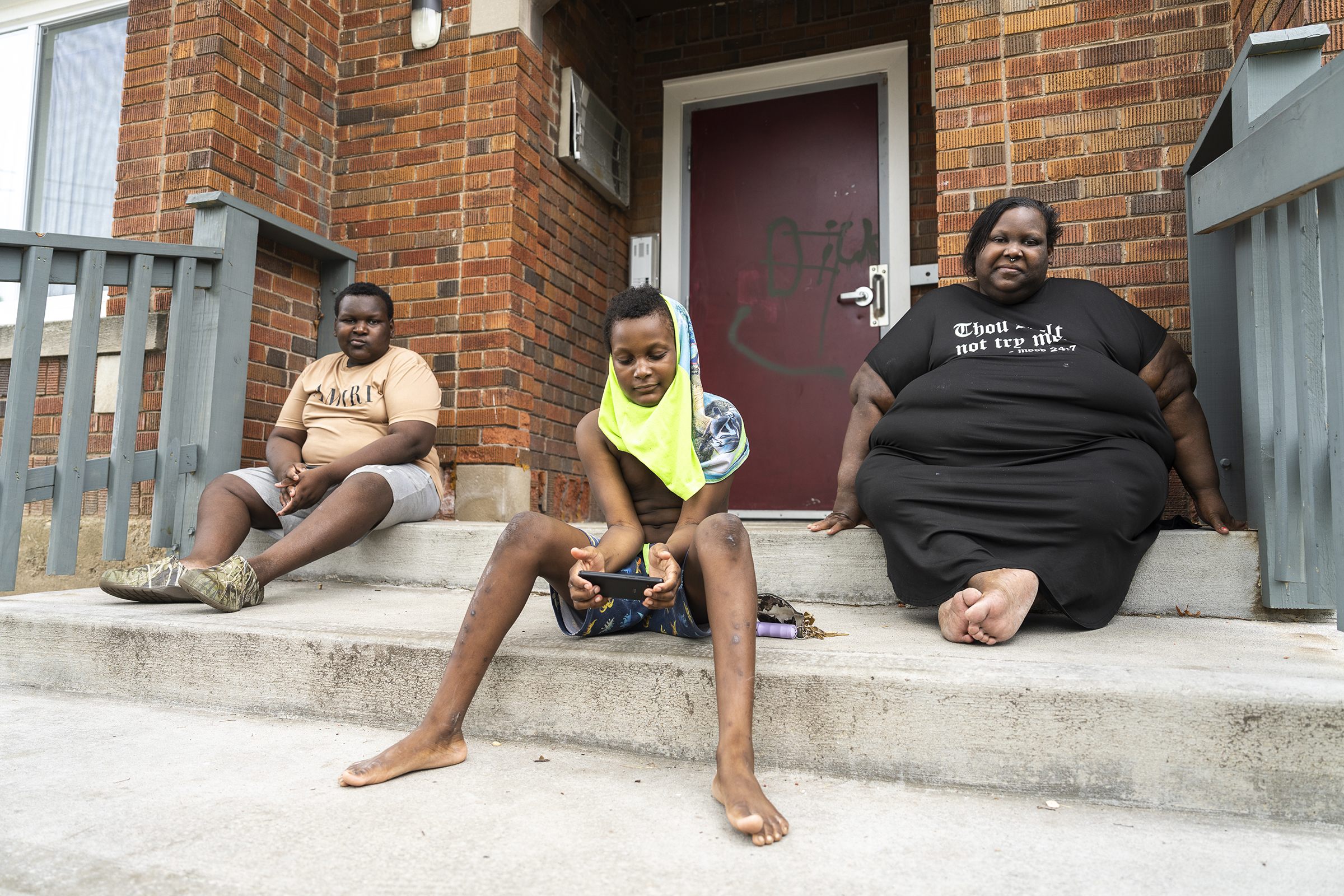 Jaidyn Jordan, 12, and Aidan Branch, now 10, sit with their mother Deanna Branch on the front stairs of a Milwaukee apartment