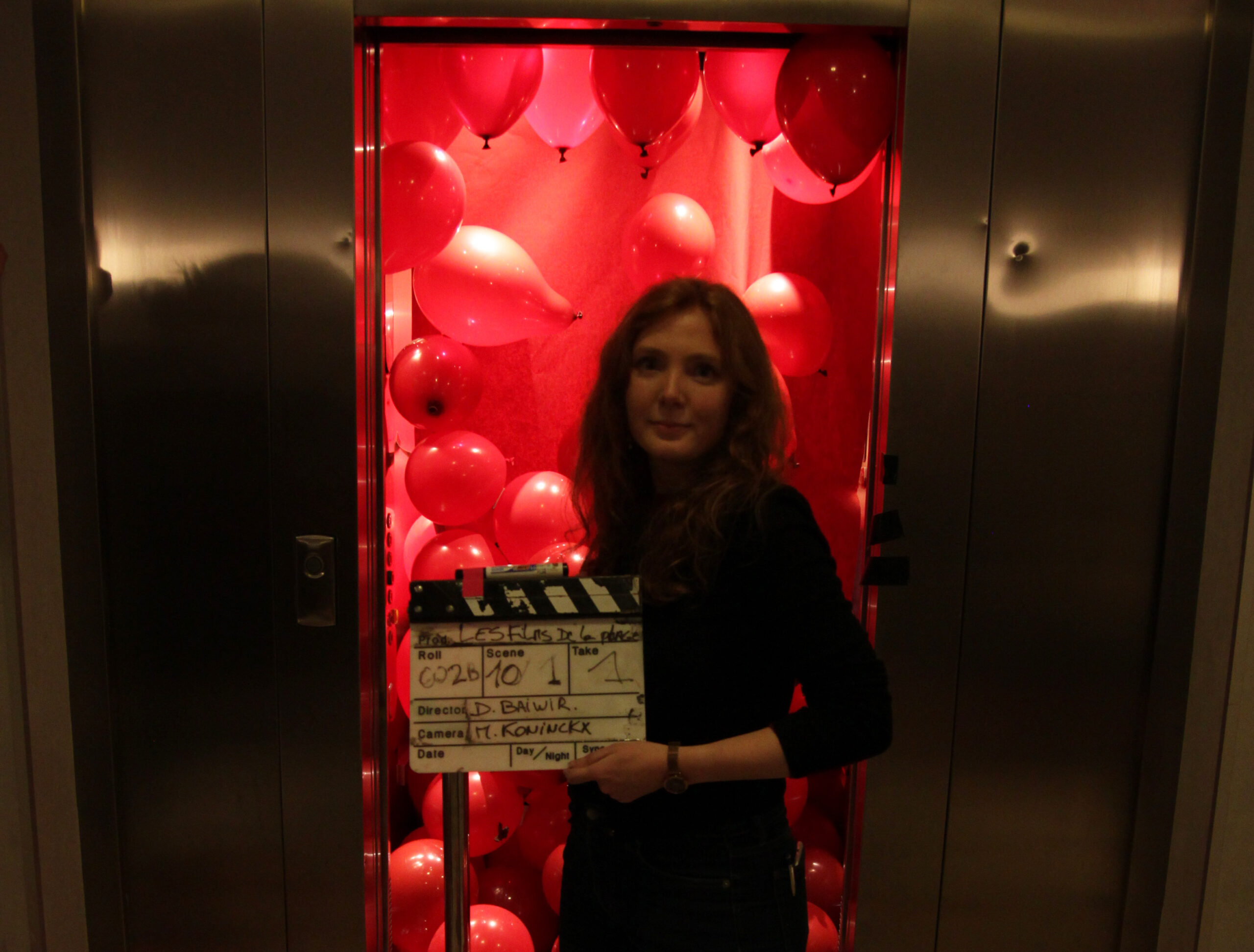 Director Daphné Baiwir in front of an open elevator filled with red balloons