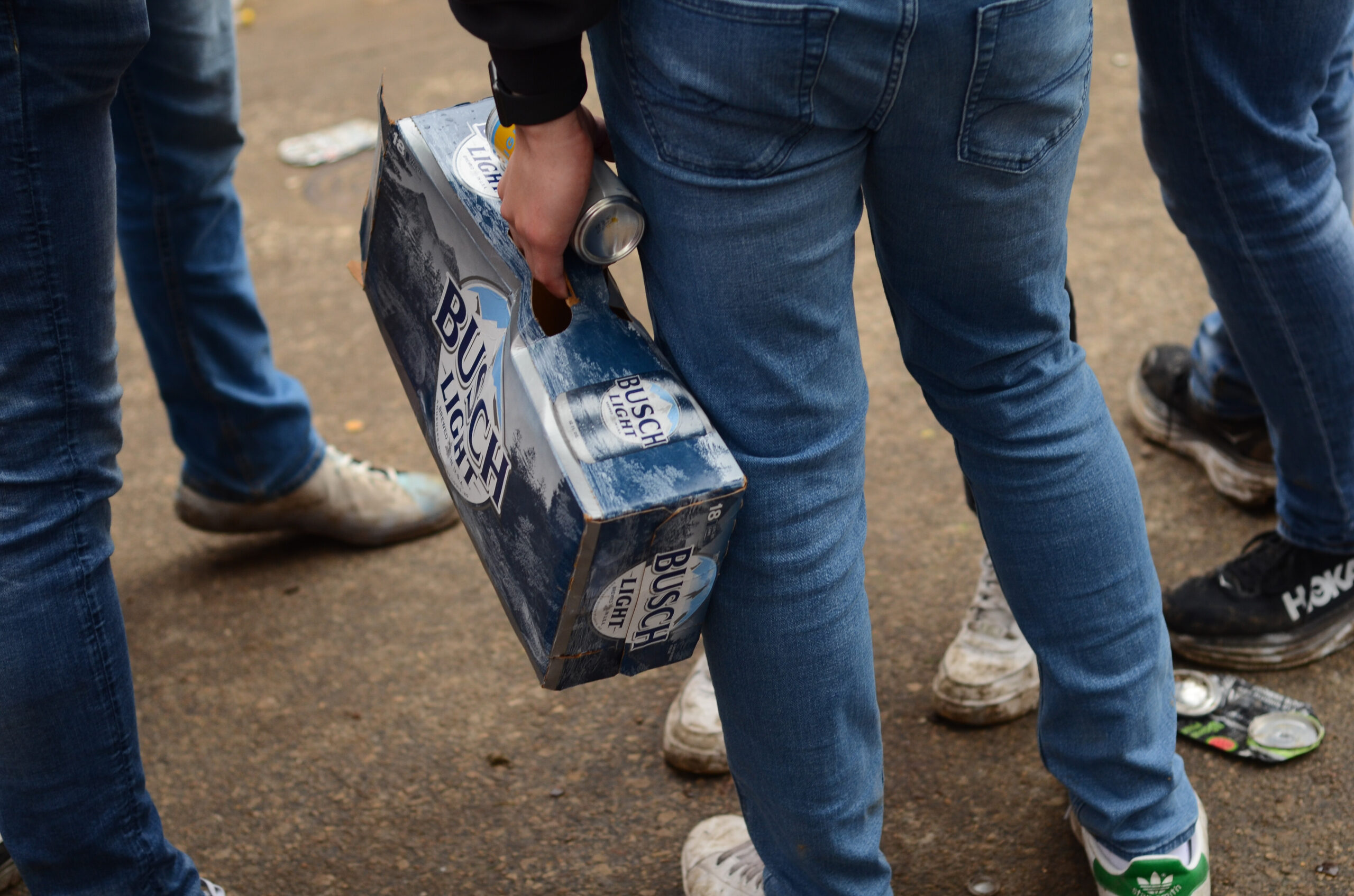 A partygoer carries an 18-pack of Busch Light