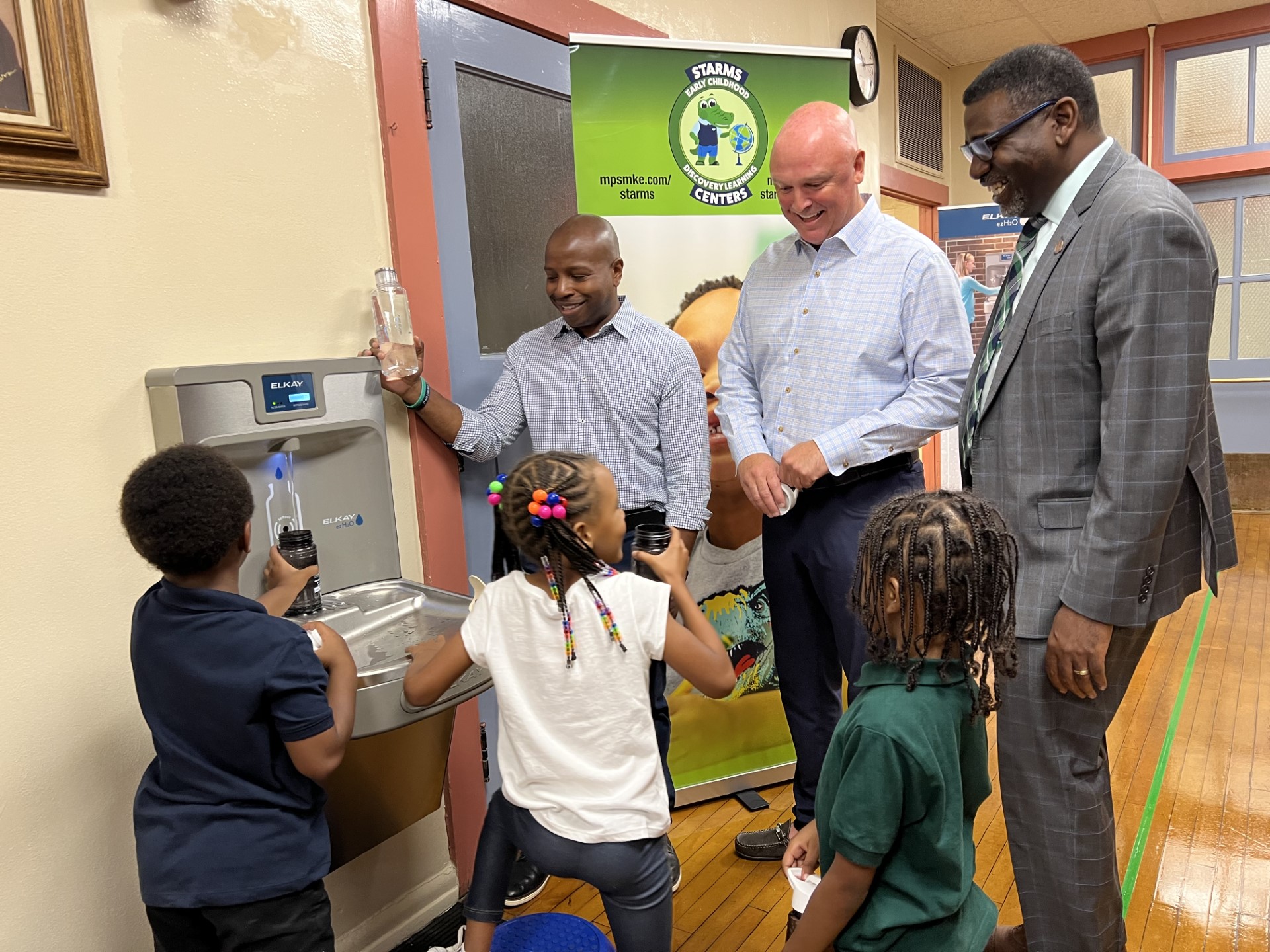 Milwaukee Mayor Cavalier Johnson helps a student at Starms Early Childhood fill up a water bottle
