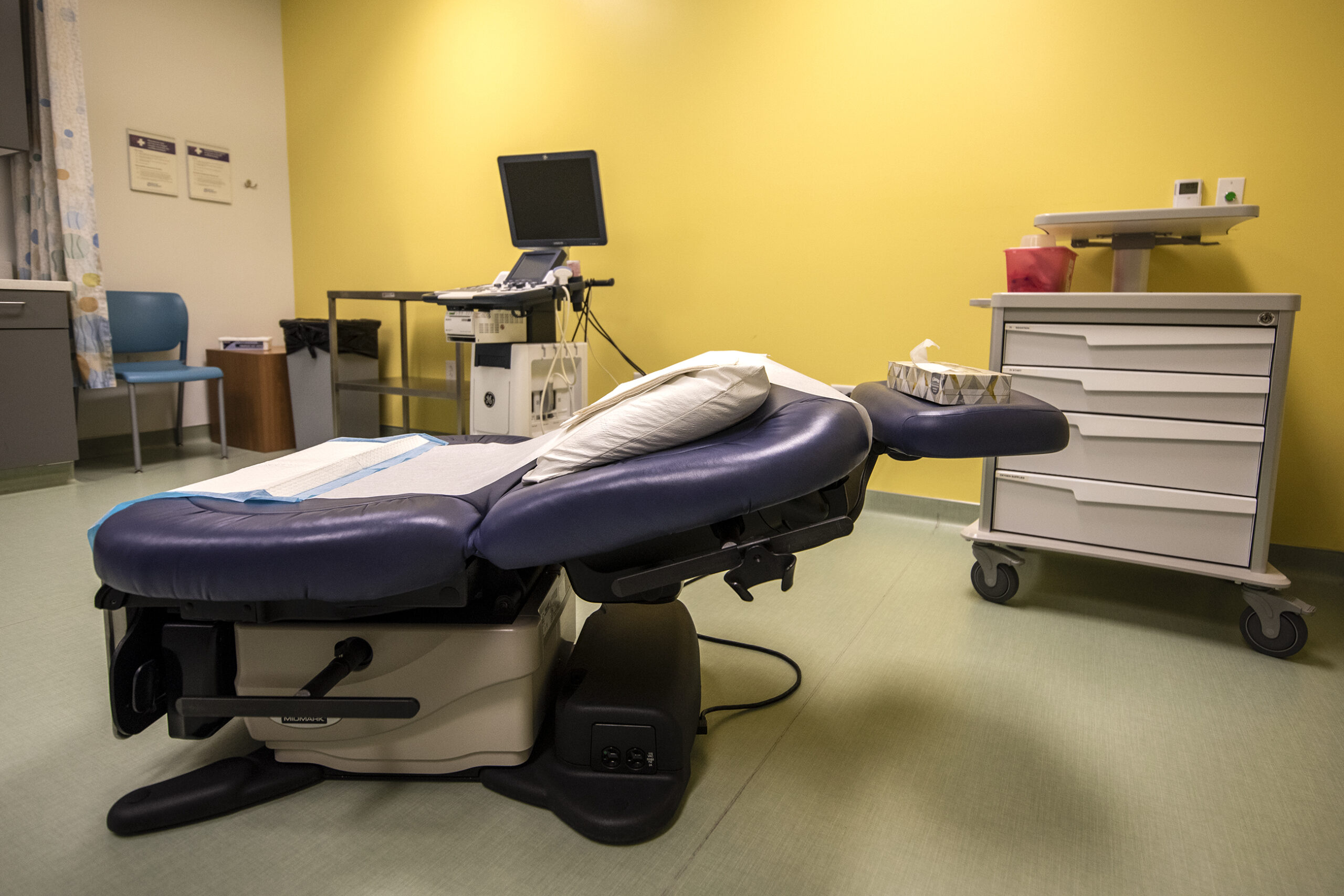 A medical chair is reclined and lined with paper.
