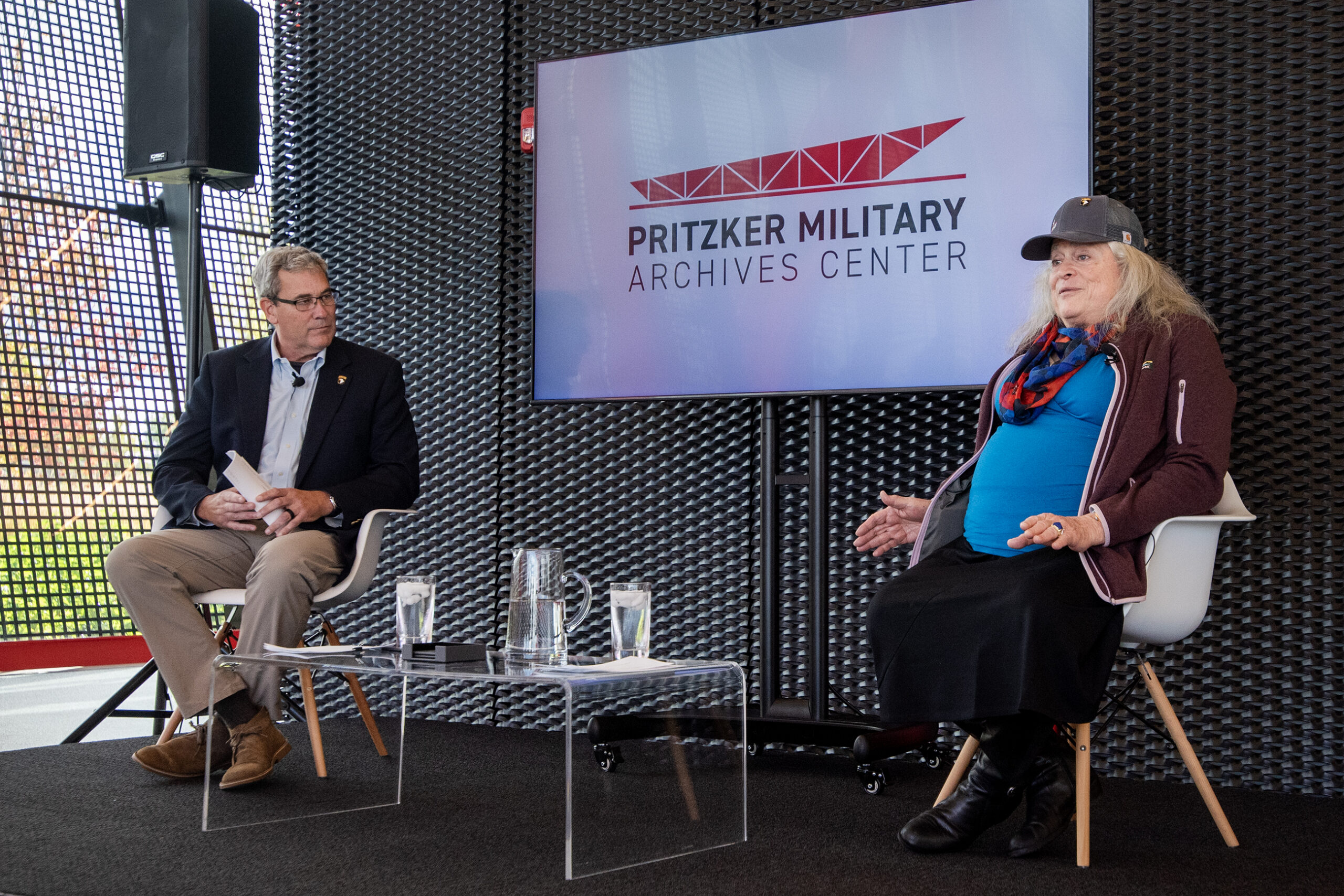 Two people sit on a stage to answer questions.