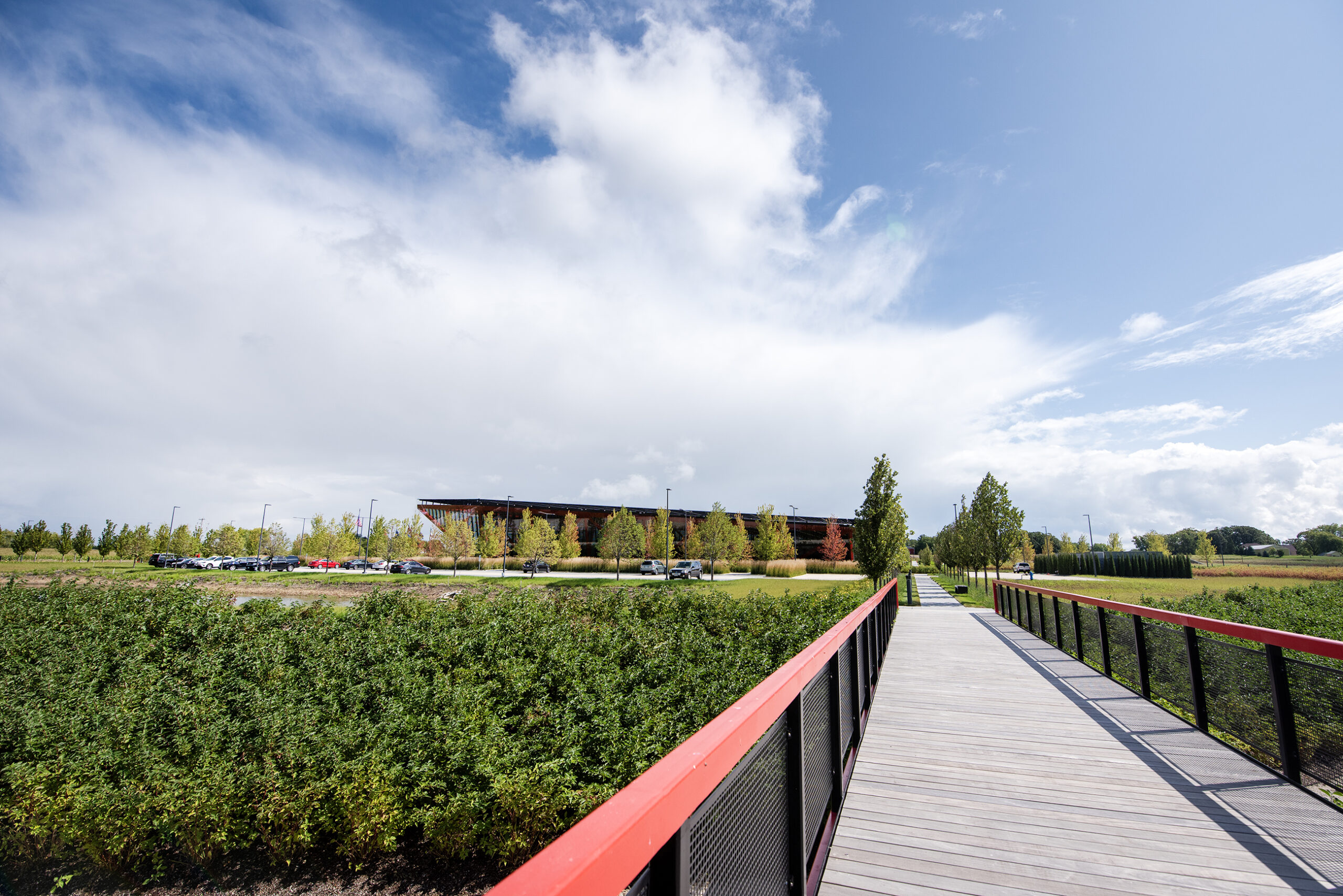 A pathway with railing that matches the red beams of the building