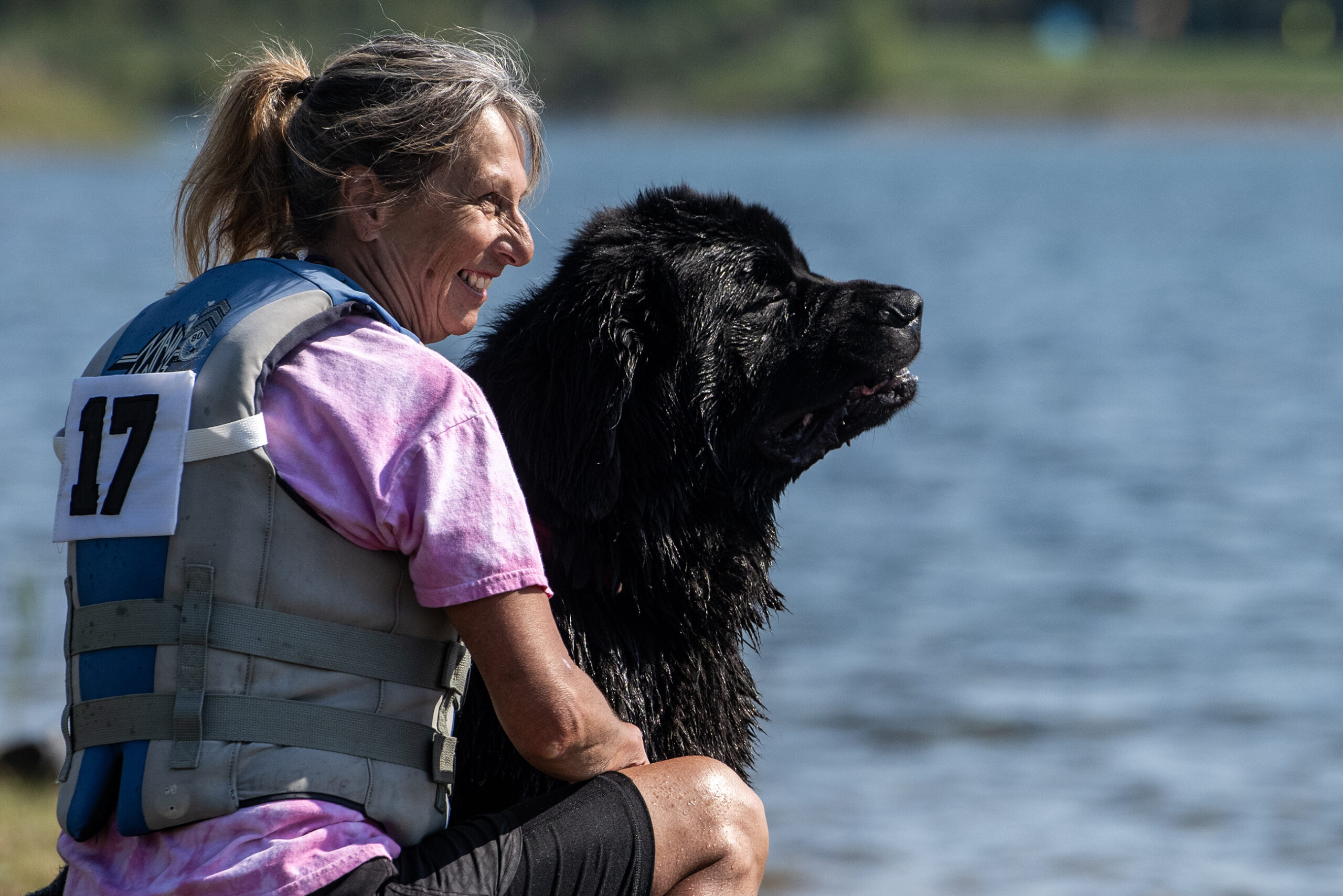 A large black dog and a woman sit next to each other.