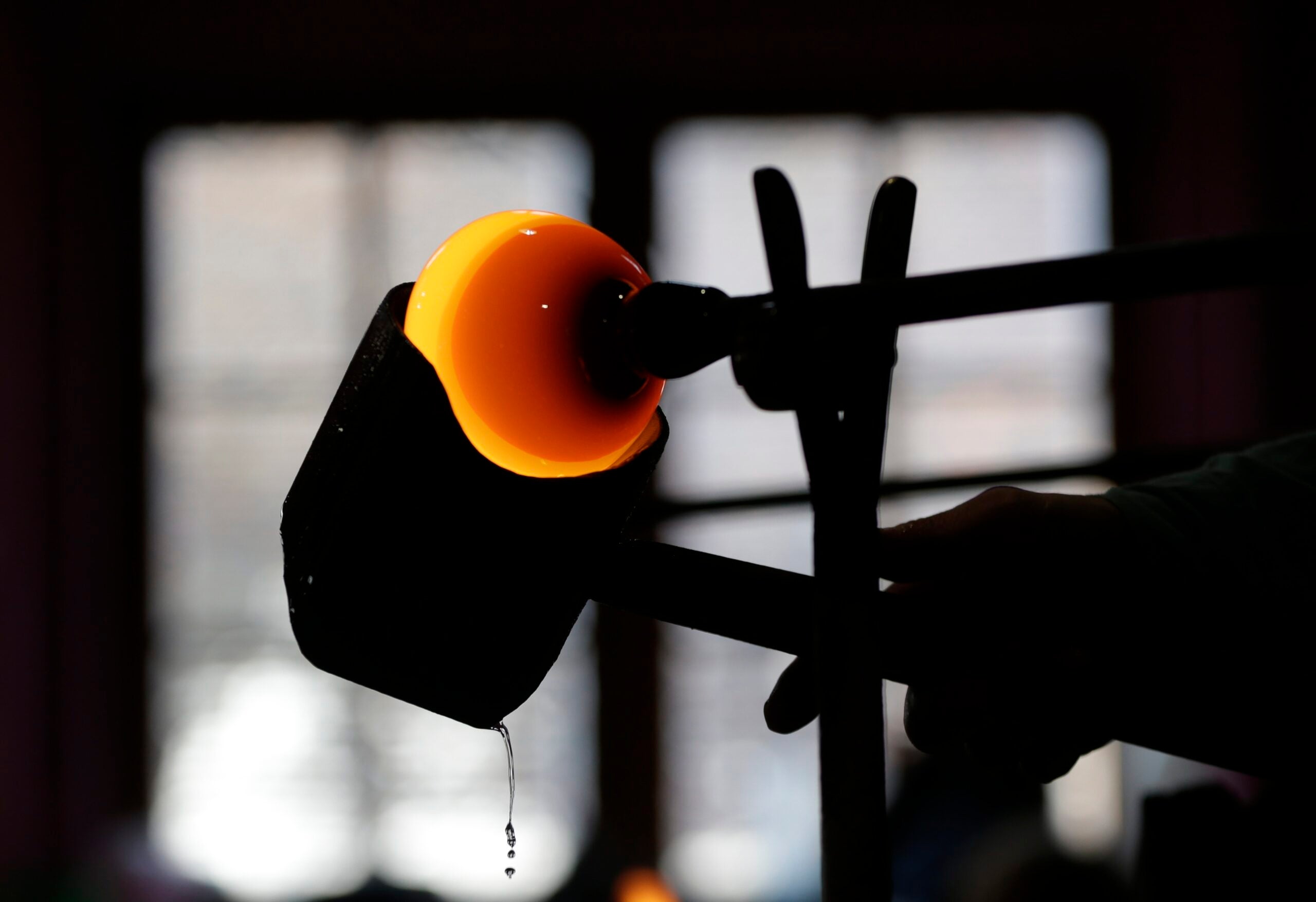 A red hot piece of metly glass is shaped by a larger object.