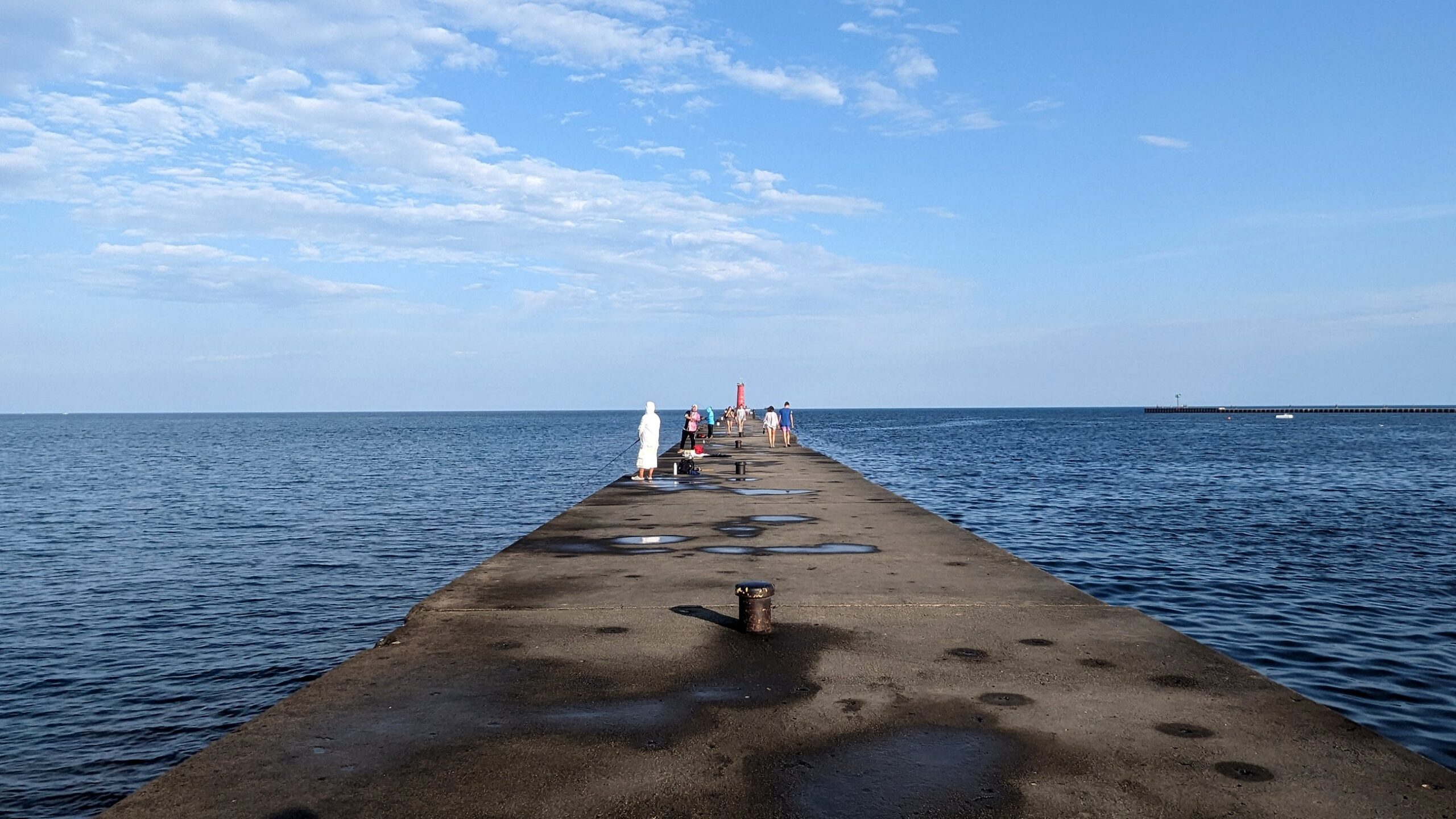 A concrete bridge with puddles extends out across Lake Michigan.