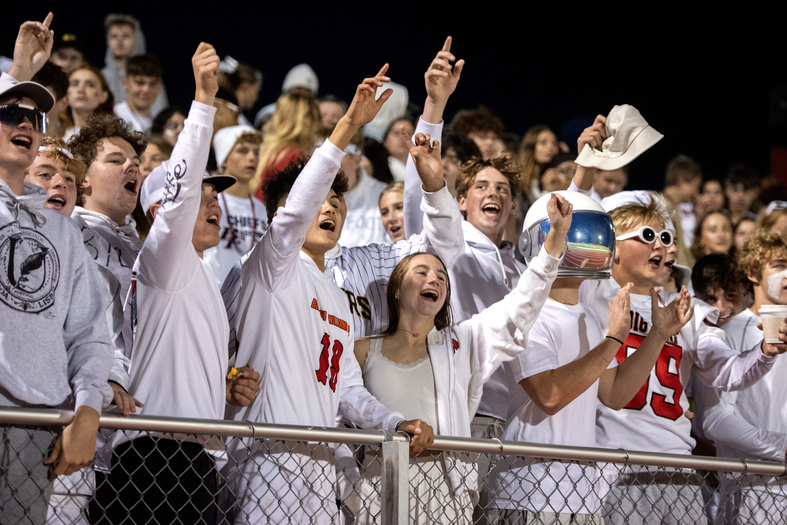Students in white and red cheer from the stands.