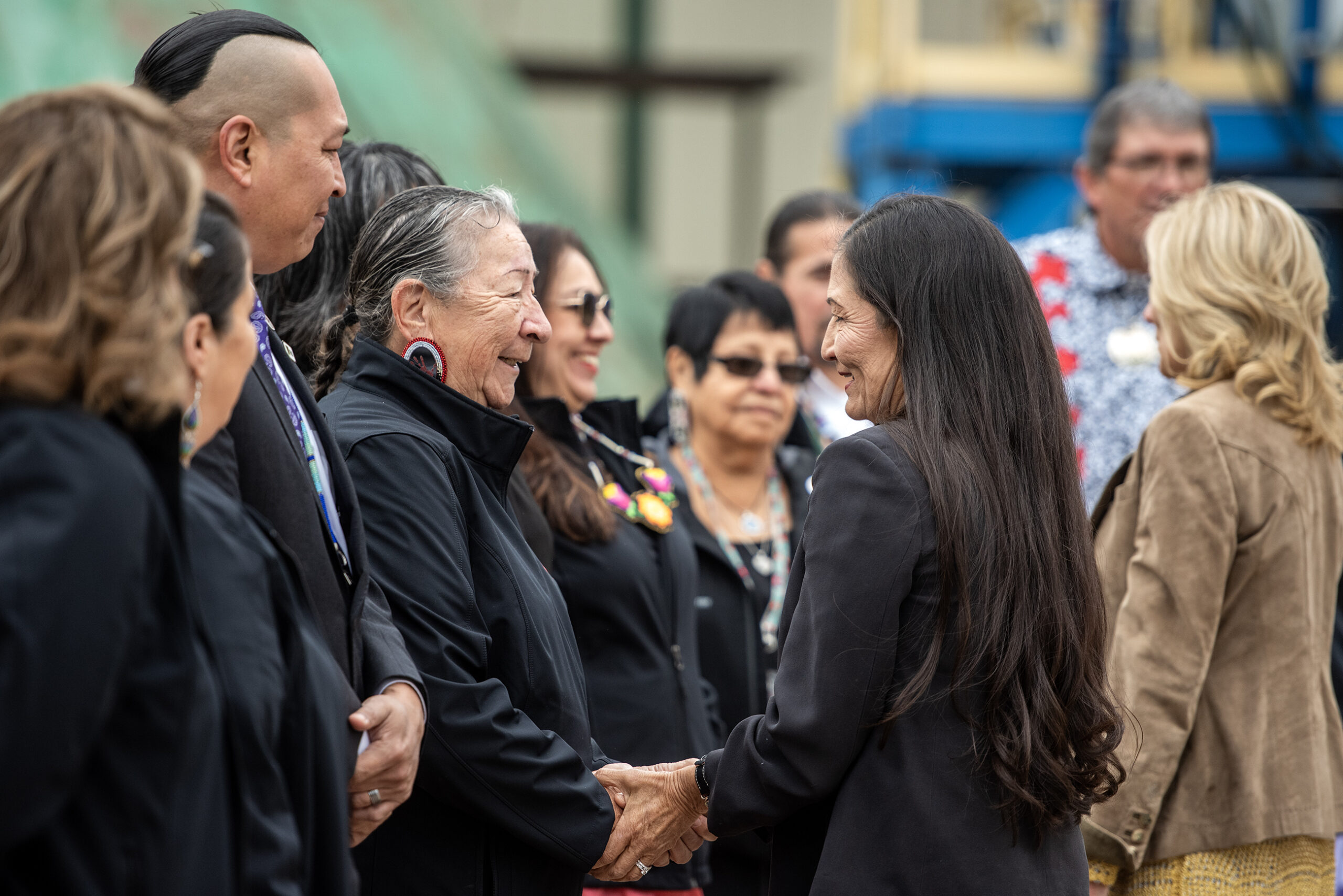 Deb Harland smiles as she shakes the hand of a woman in a line of other leaders.