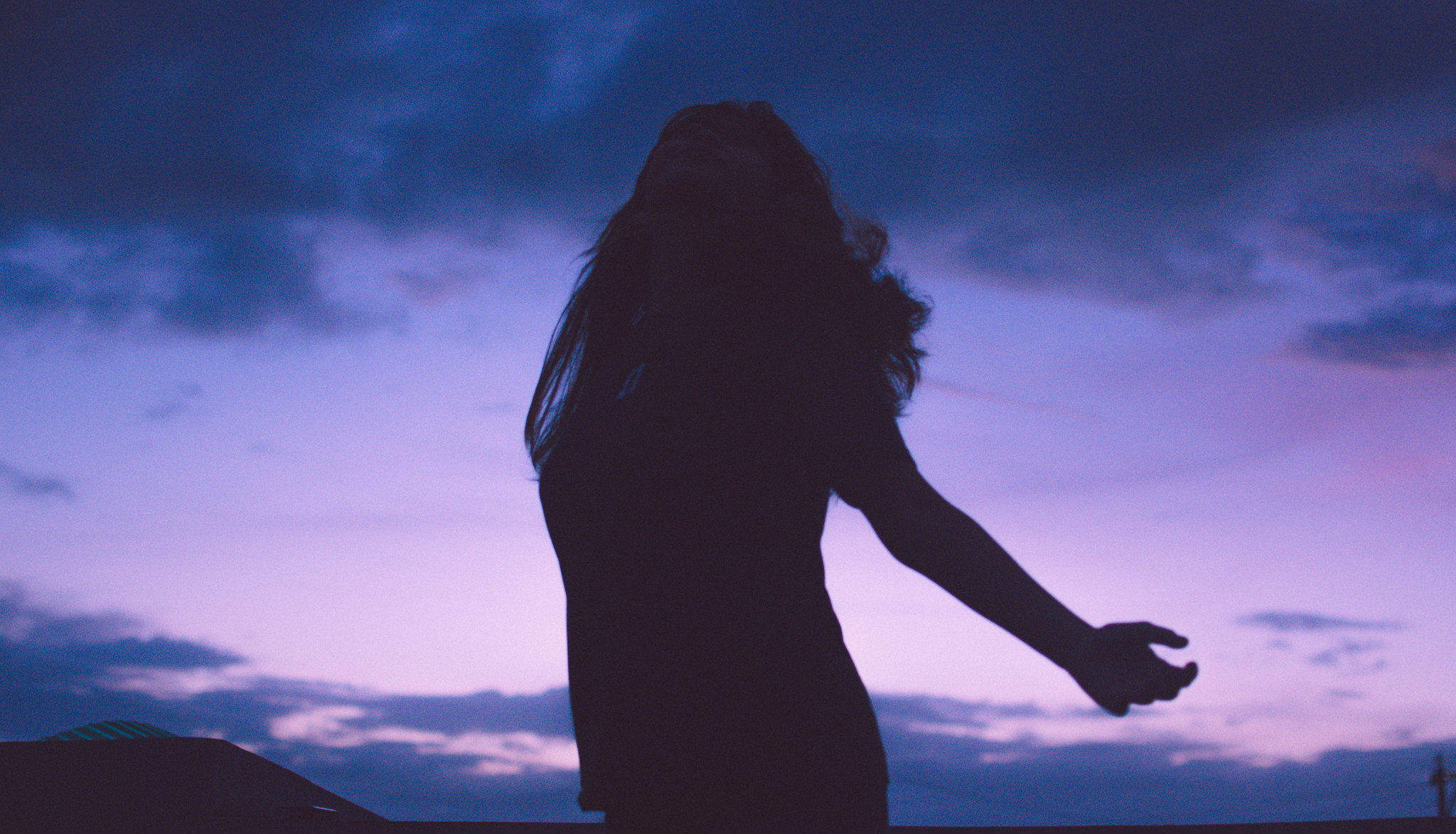 A silhouette of a woman against a purple night sky