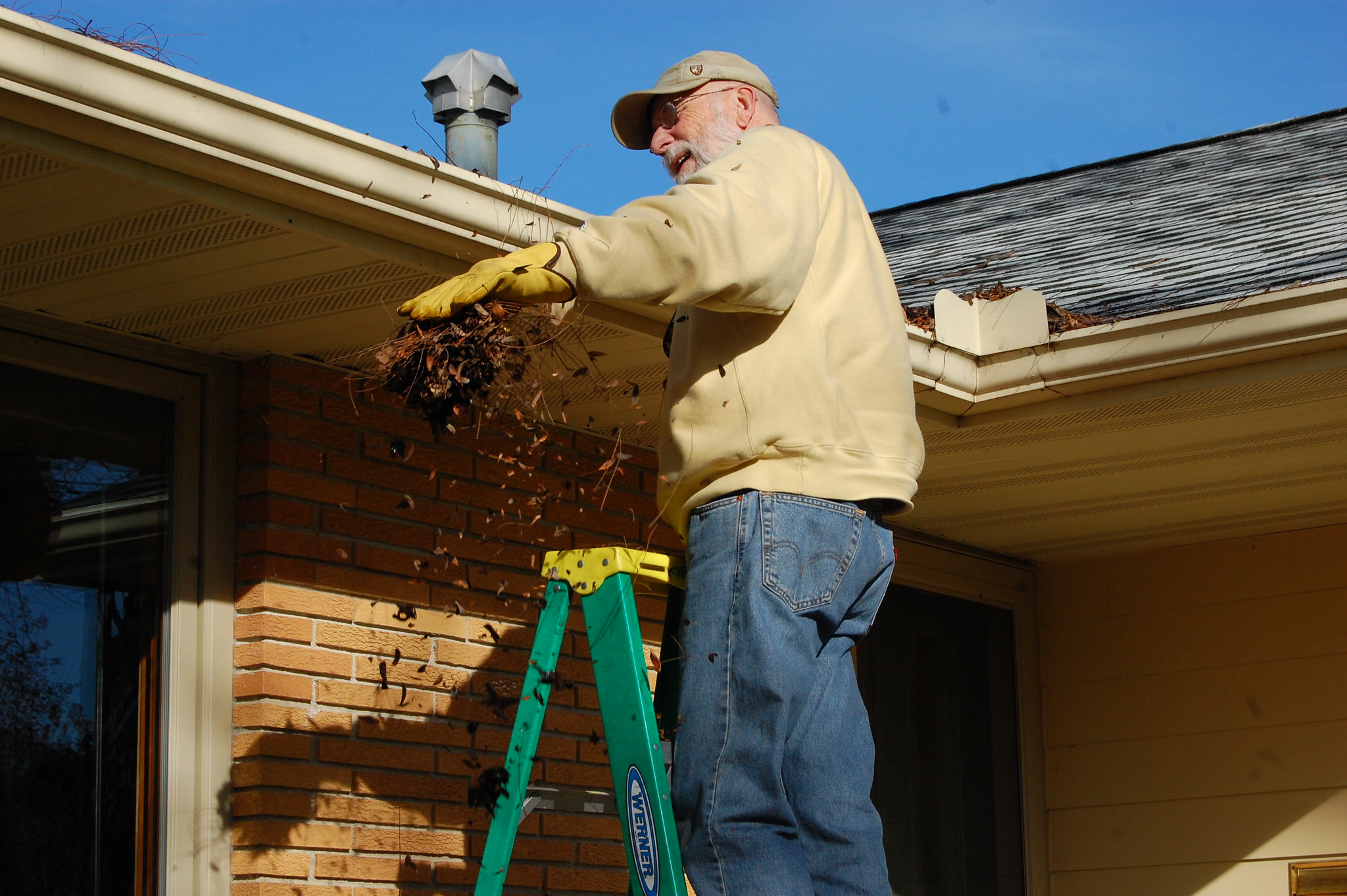 Man cleaning leaves from gutter.