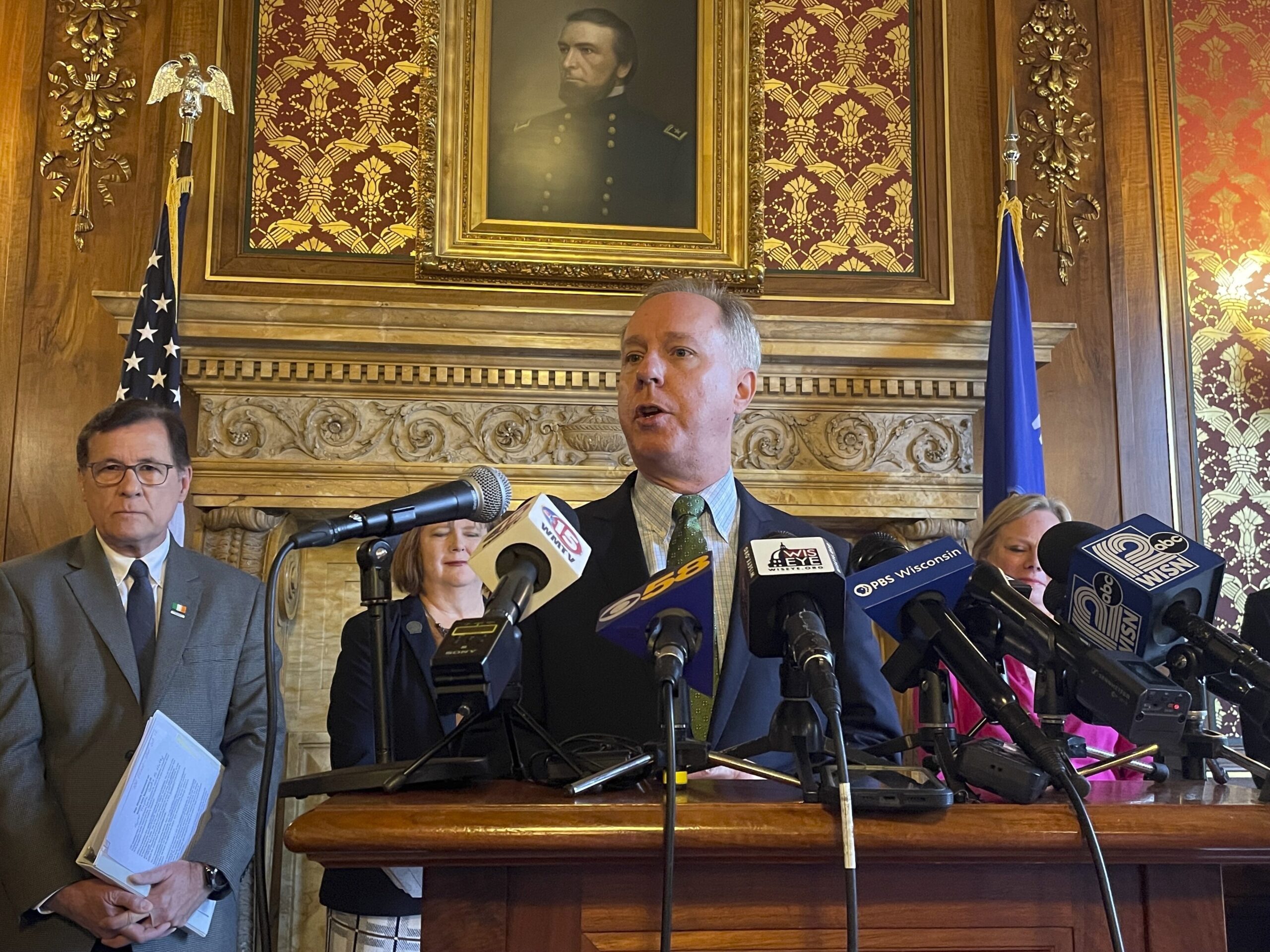 Wisconsin Assembly Speaker Robin Vos standing at a podium during a new conference with people behind him