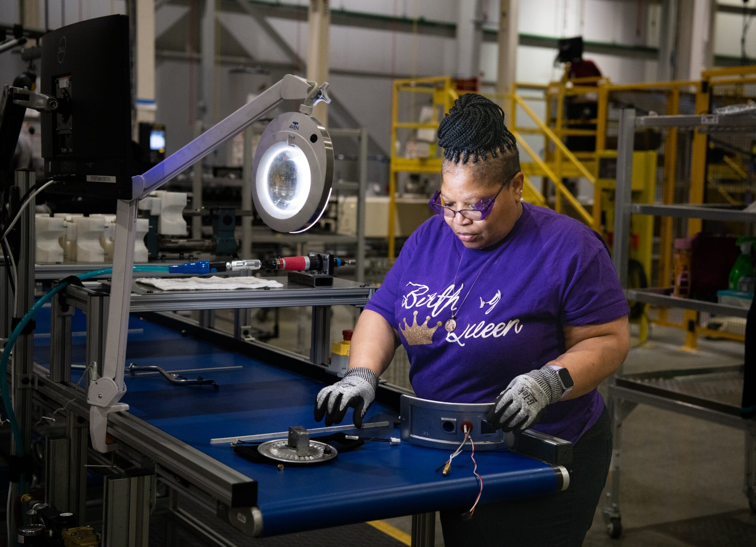 A woman works at a factory table to build water heaters