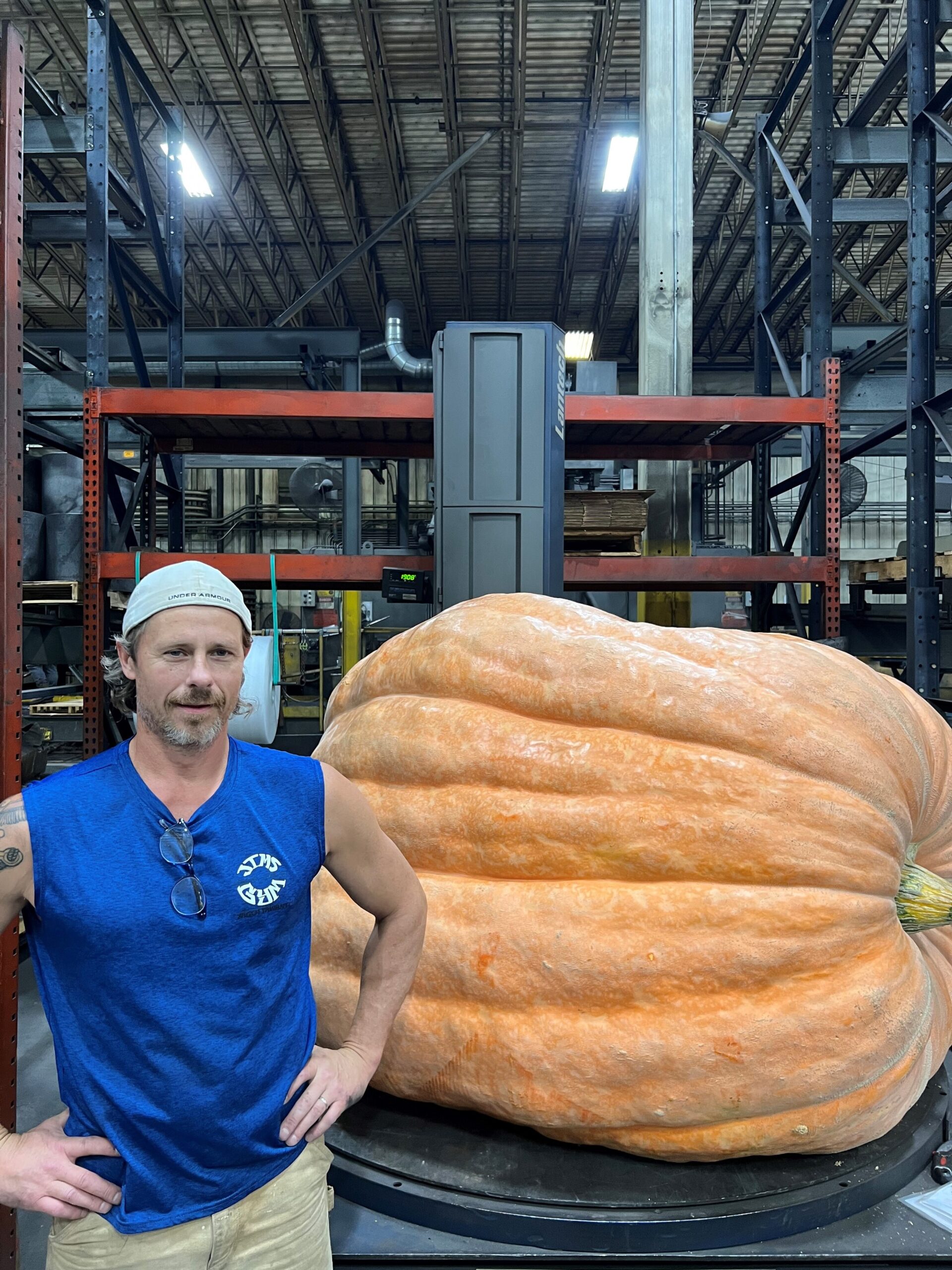 Jim Suchanek poses with his hands on his hips next to a nearly 2,000-pound pumpkin