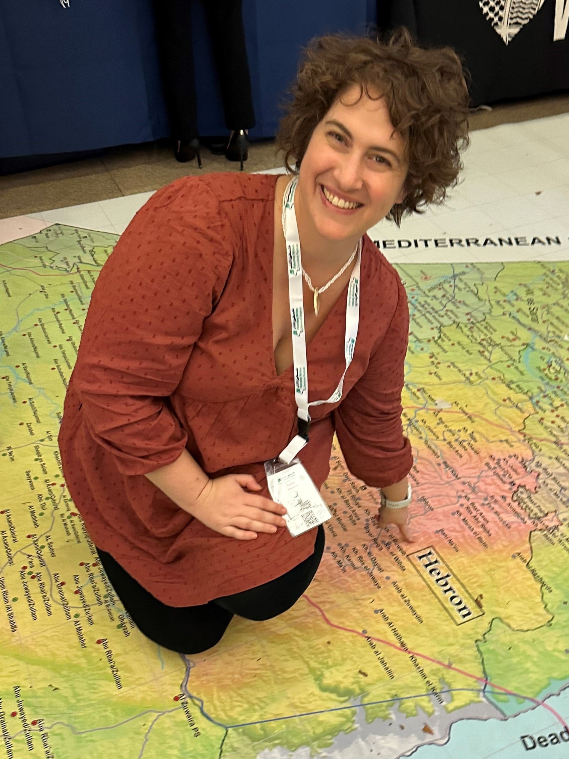 Sarah Manasreh kneels on a large map