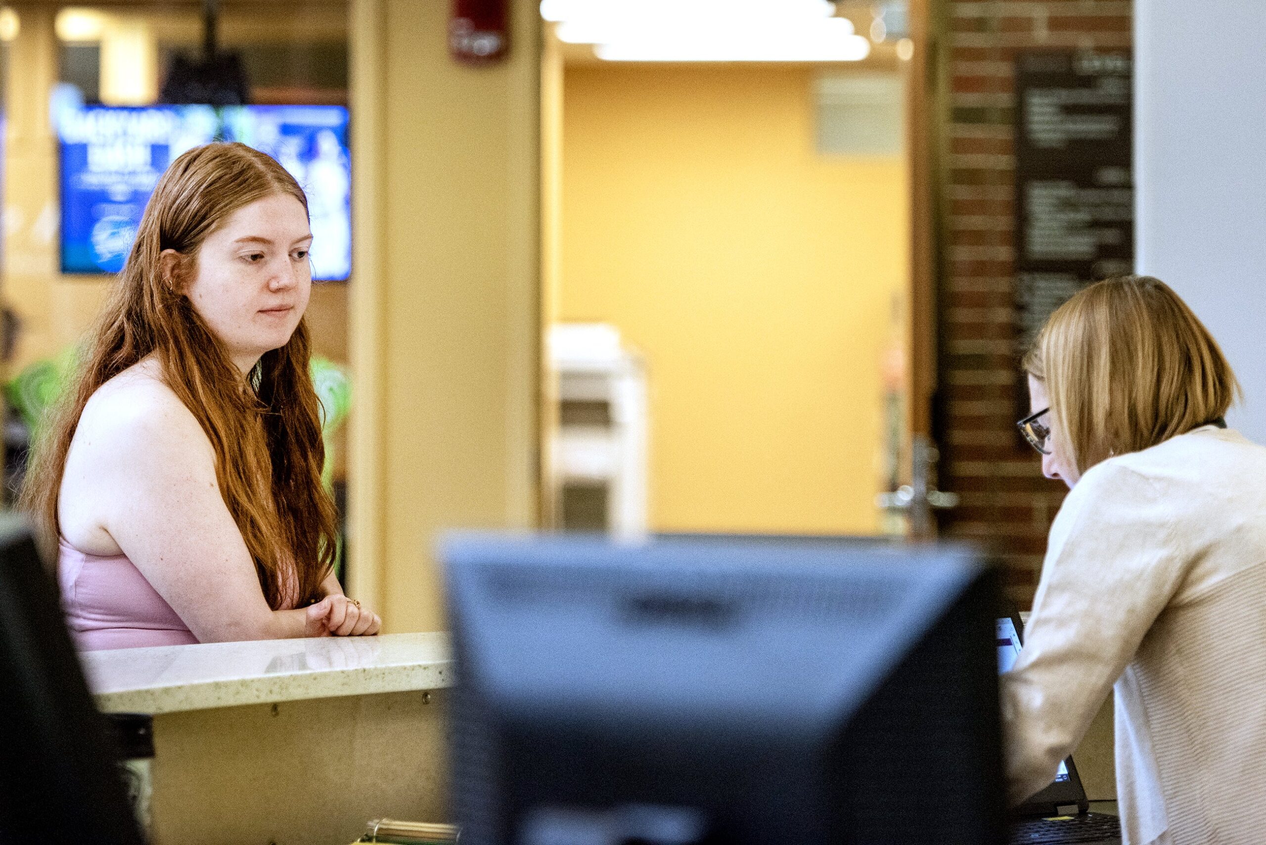 A student stands at a counter to speak to a worker.