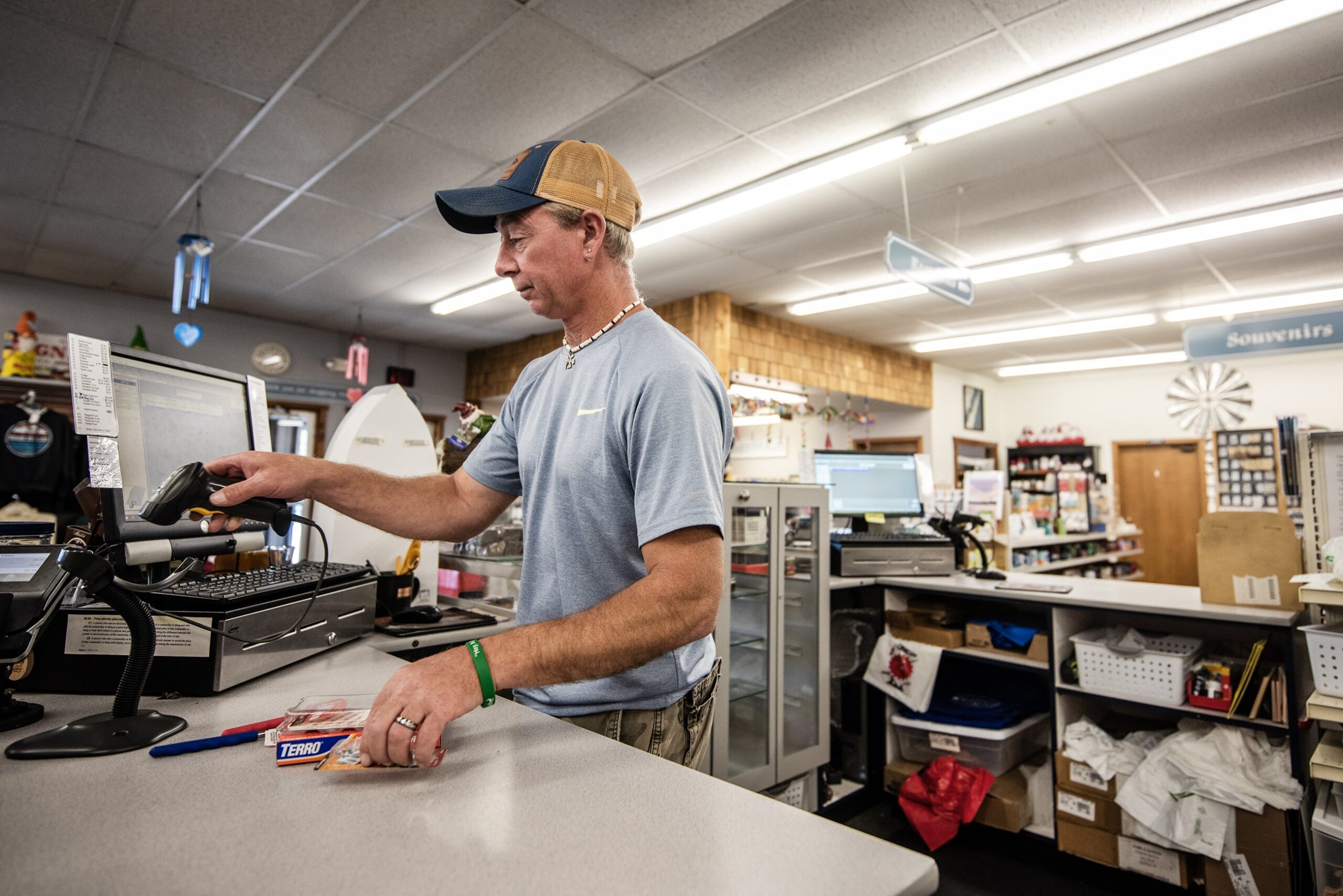 A cashier scans items with a handheld scanner inside a shop.