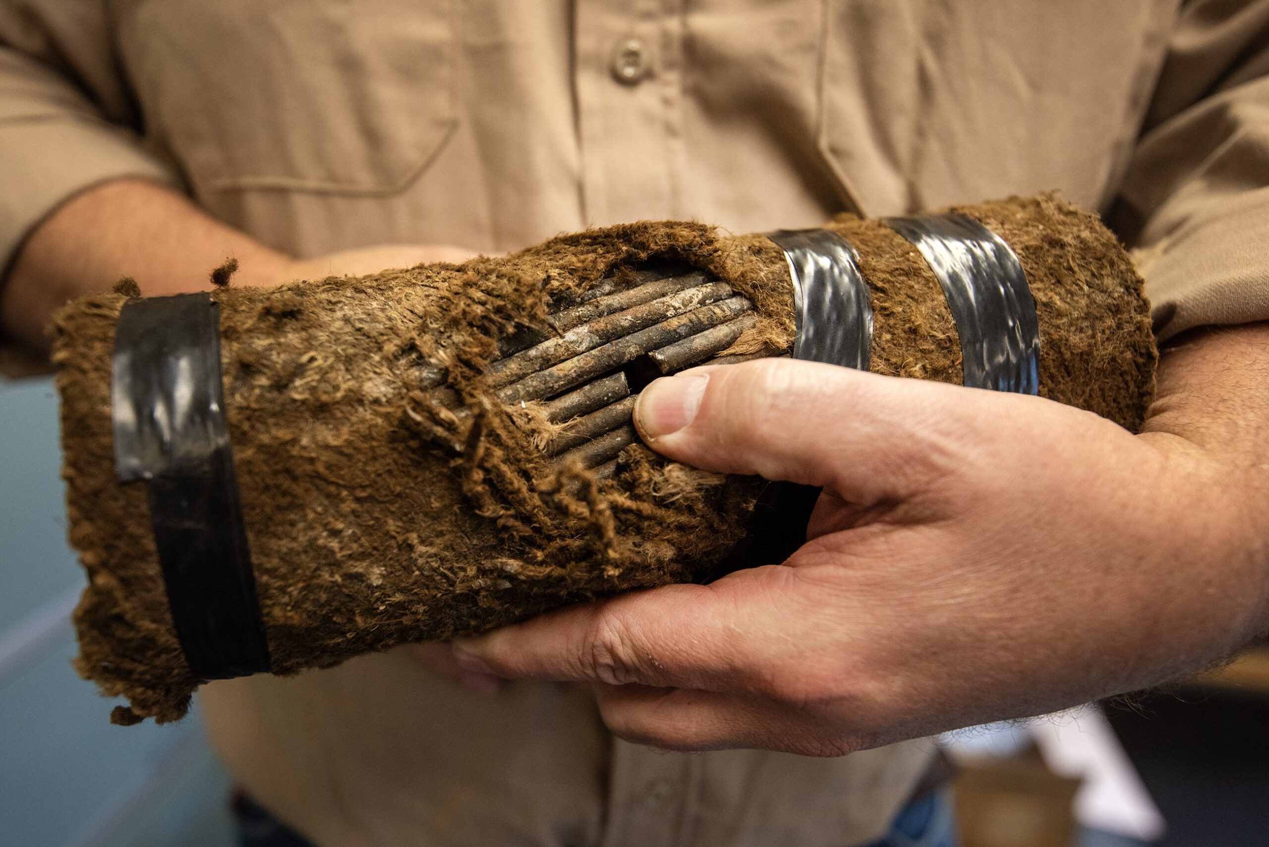 A man holds a piece of cable showing a hole that was pierced into it.