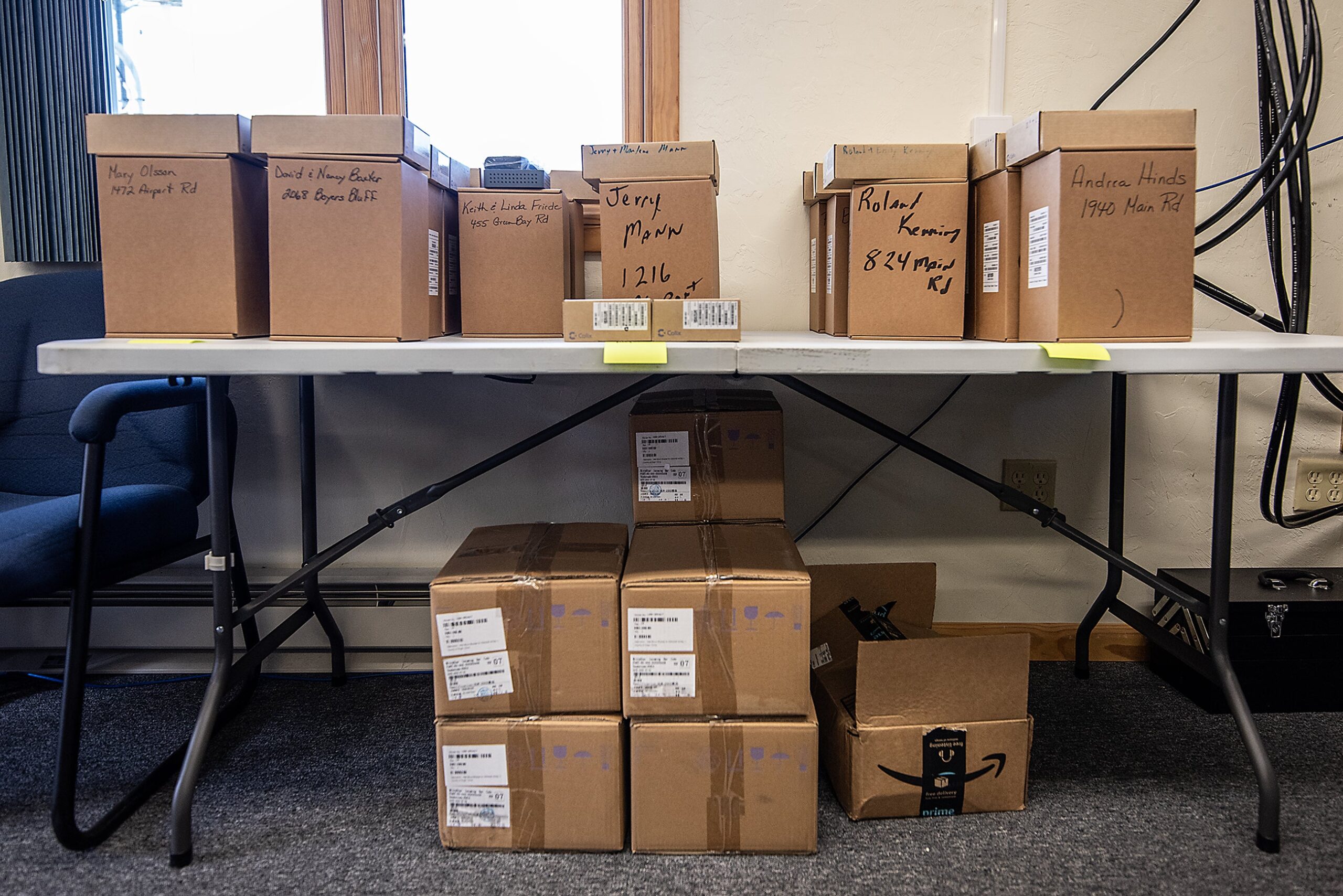 Small cardboard boxes have the names of residents written on them as they sit on a table.