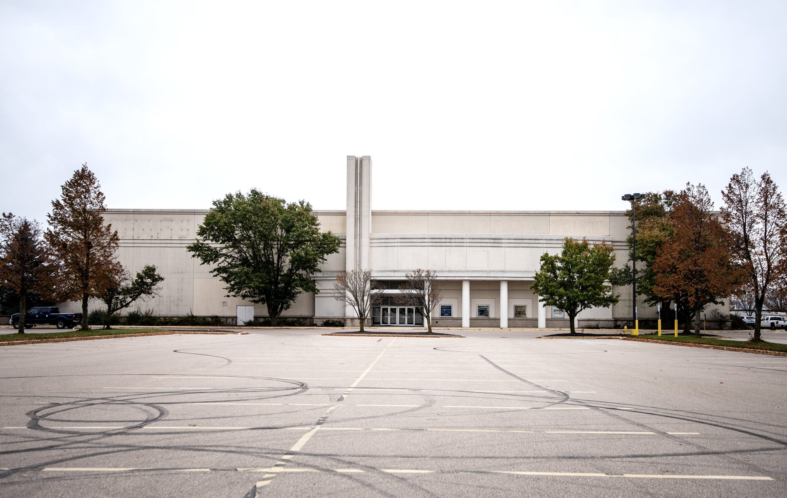 A parking lot in front of a closed Sears store has tire marks.