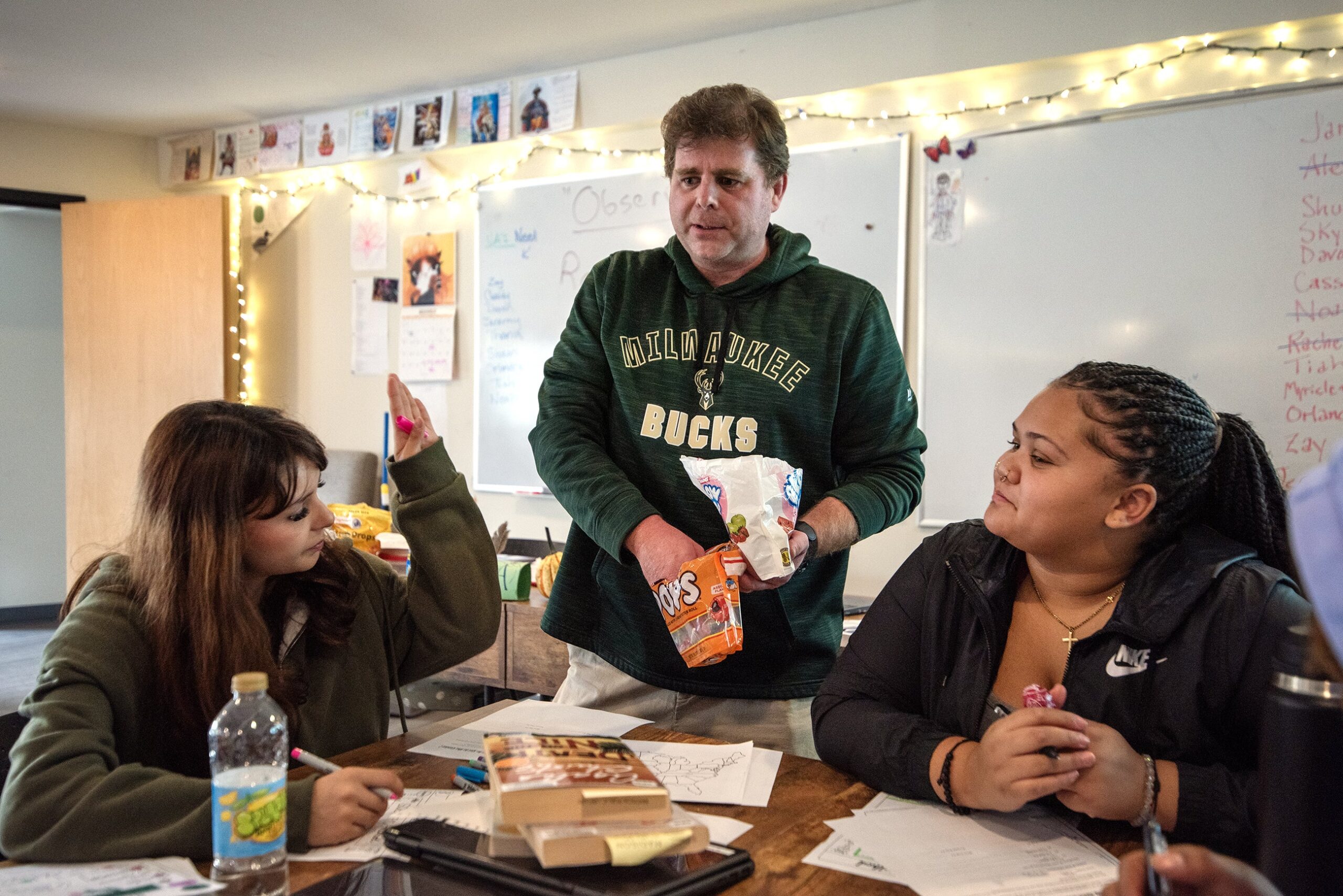 A teacher stands at a table where students are sitting.