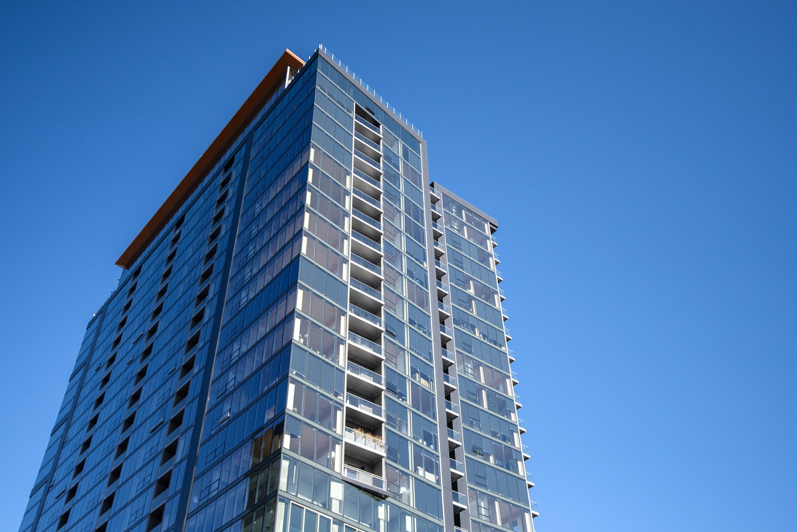 A clear blue sky can be seen from a view below the tall building.