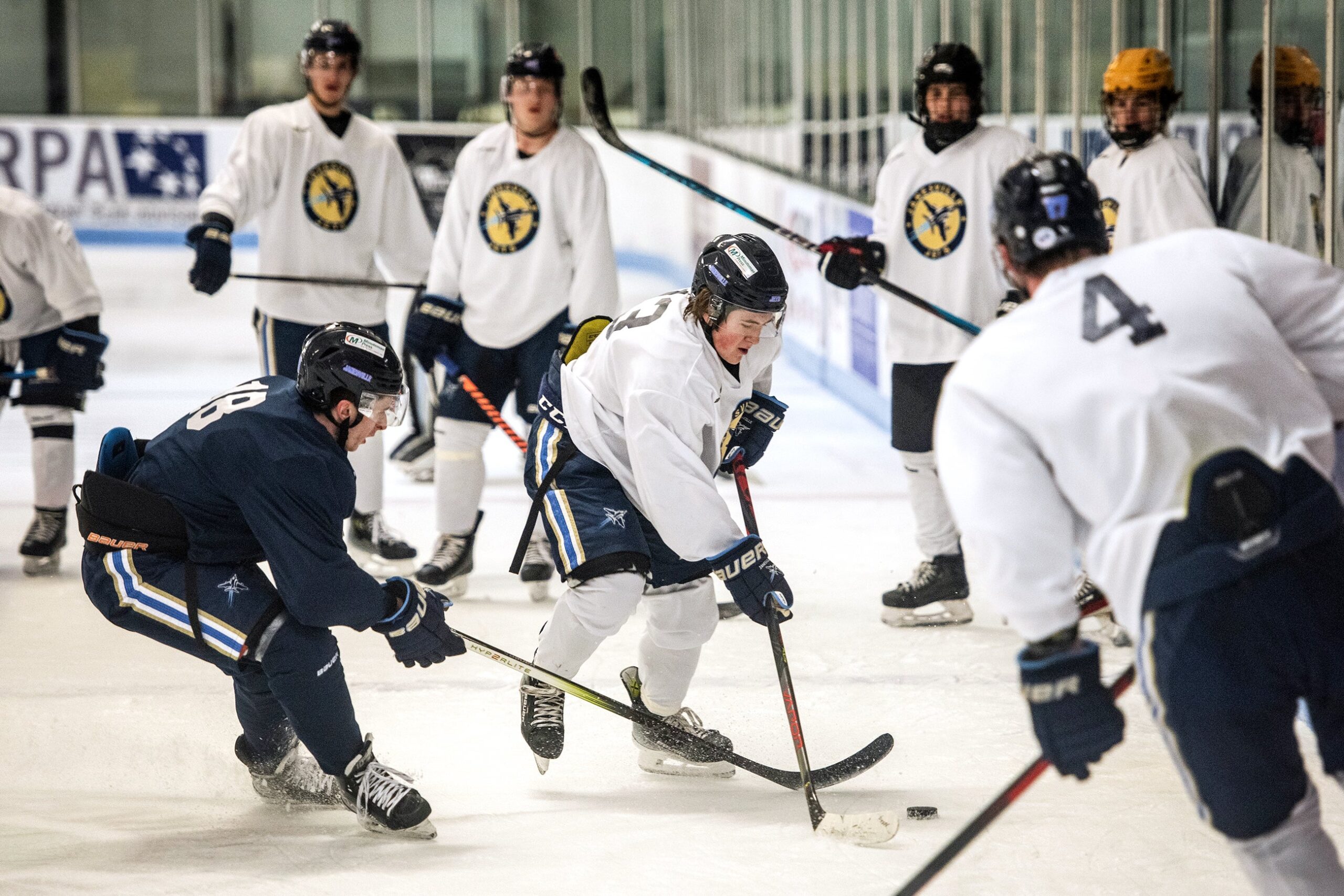 Several players fight for the puck on the ice during practice.