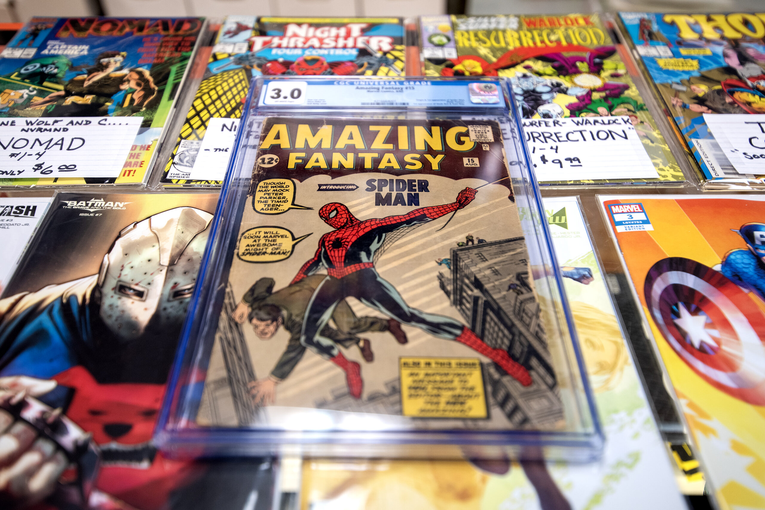 A comic book is kept in a protective case. Spiderman can be seen on the cover.