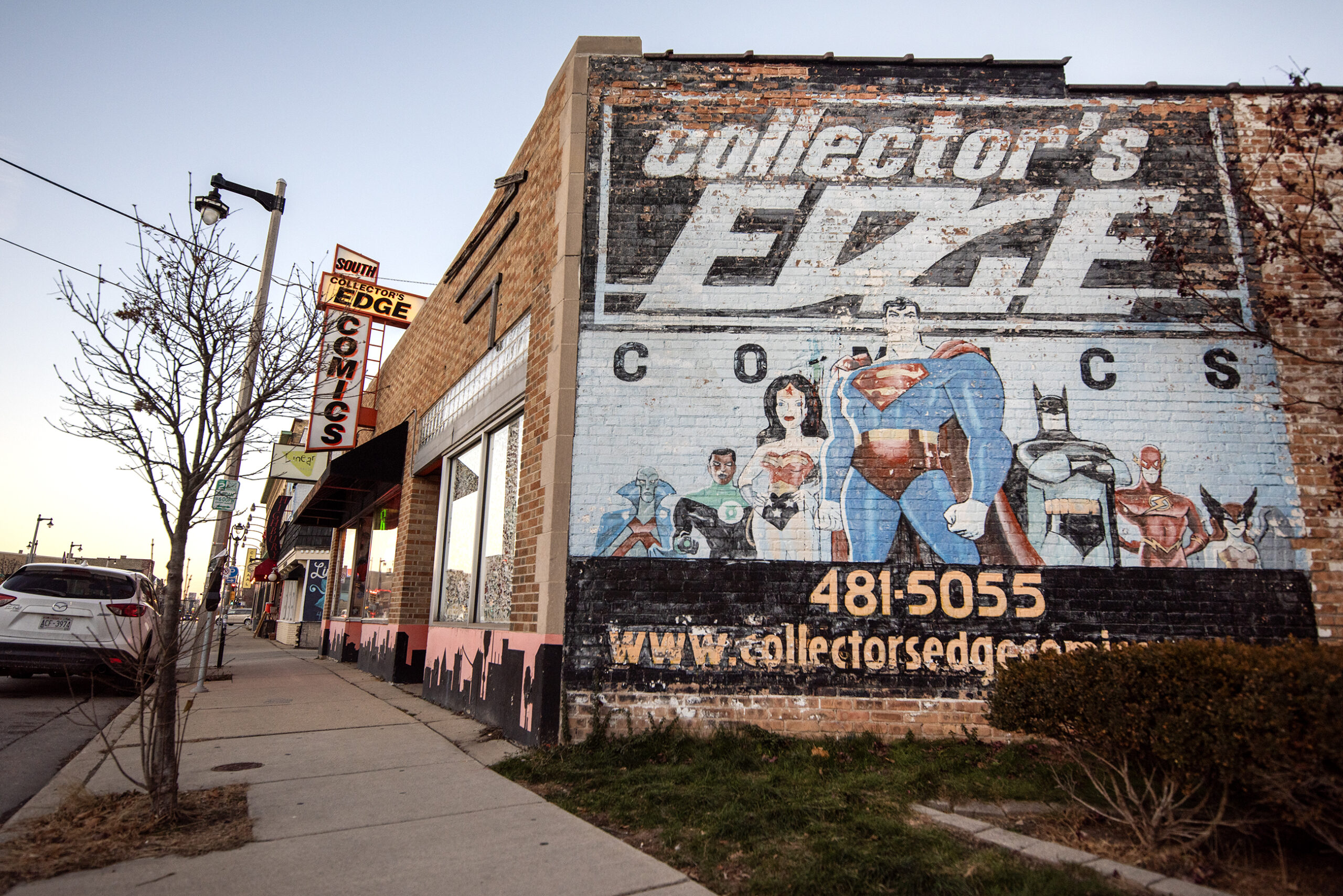 A mural on the side of a brick wall shows the store's name along with superheroes.