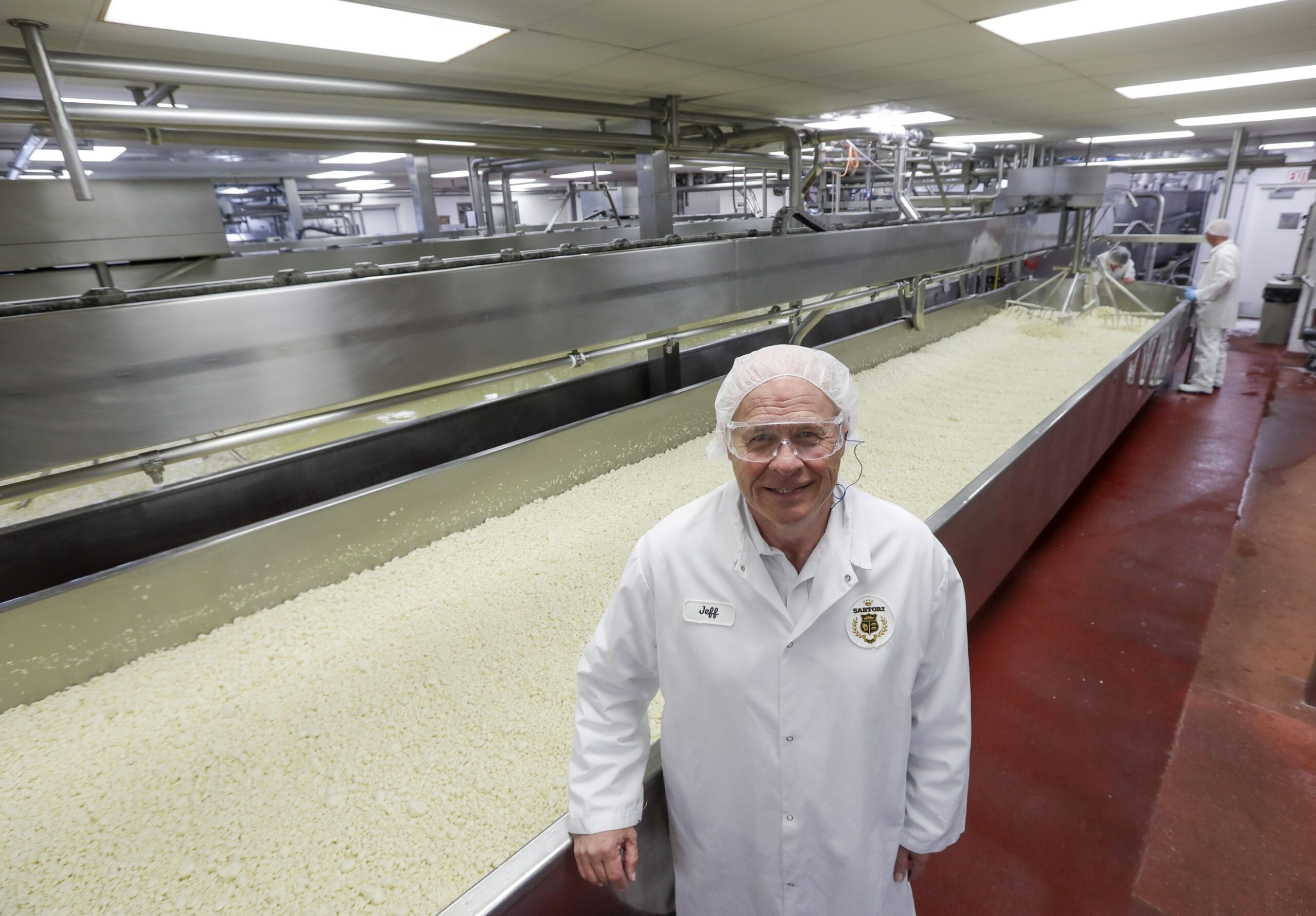 A person standing in front of cheese manufacturing operation