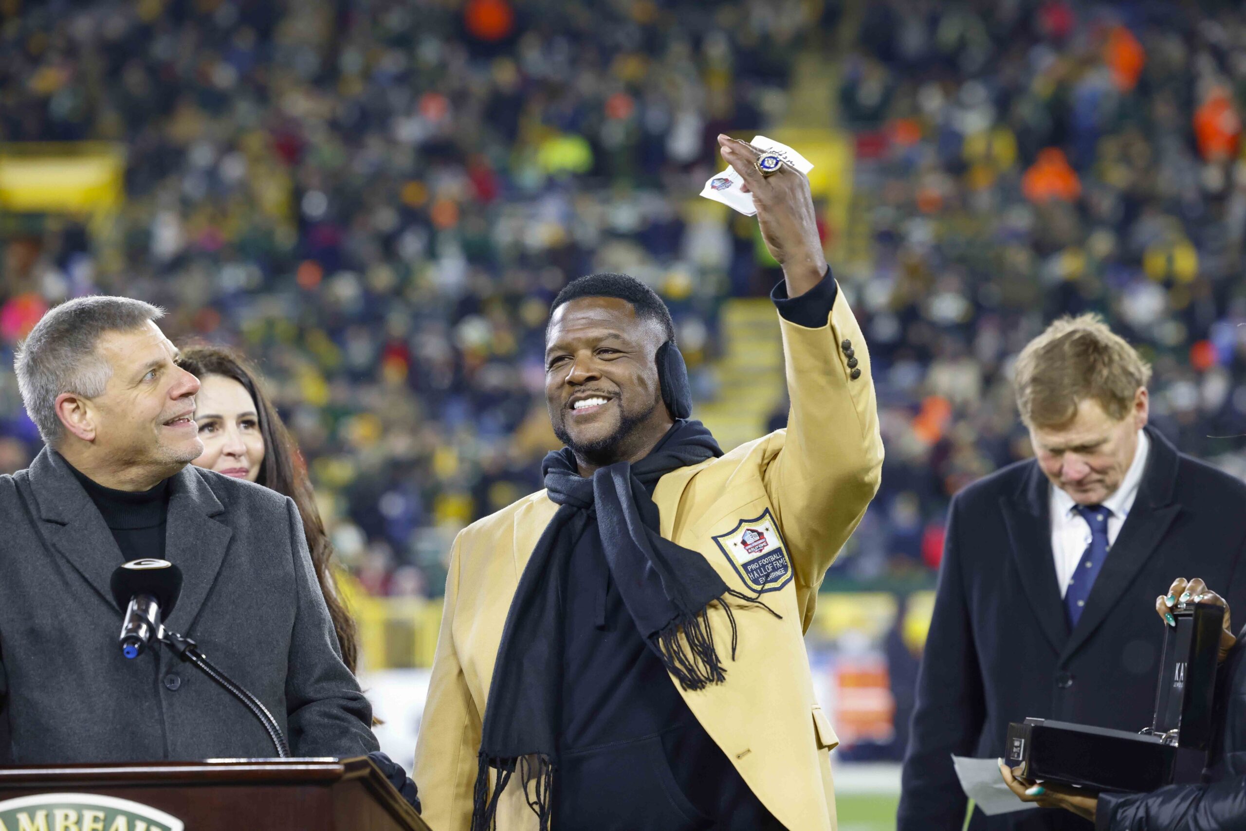LeRoy Butler holds up a hand featuring a Super Bowl ring in front of a crowd at Lambeau Field