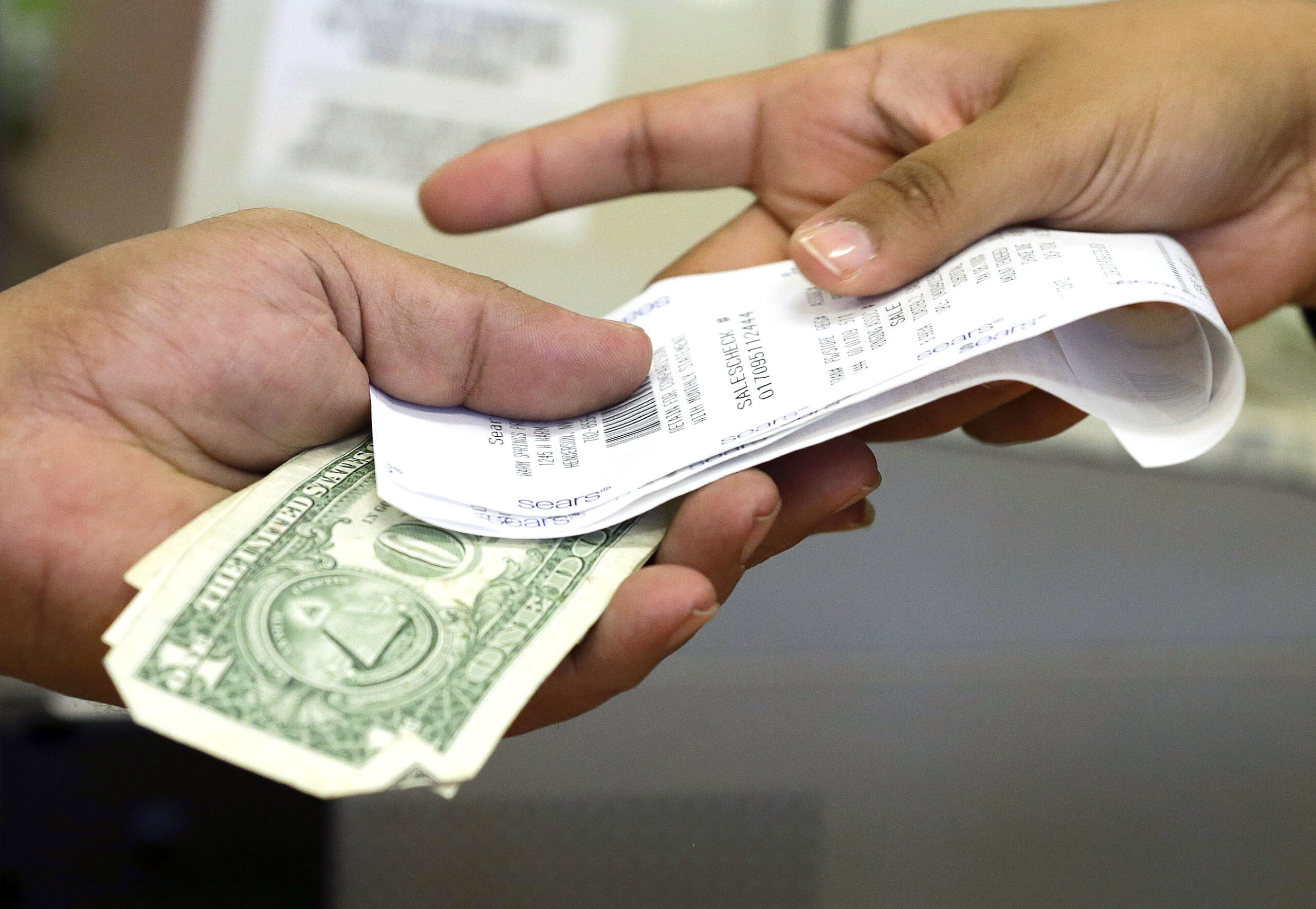 A cashier hands a customer his receipt