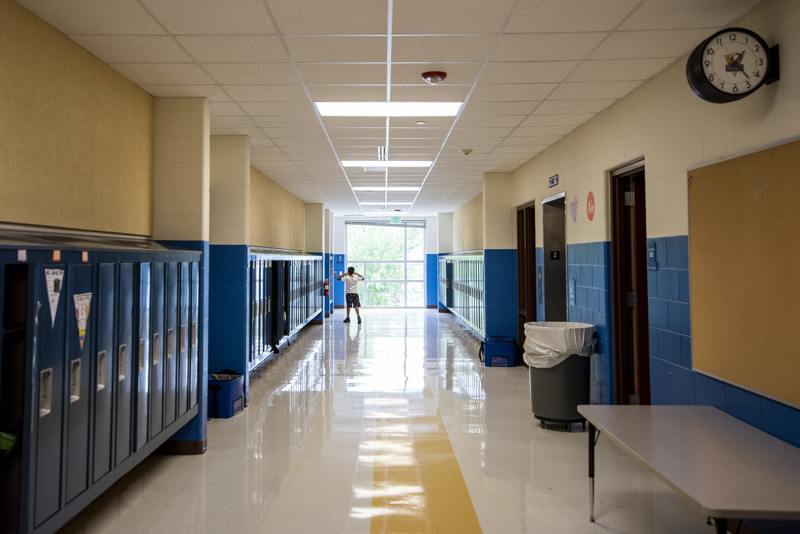 Blue lockers line a hallway in a school building.