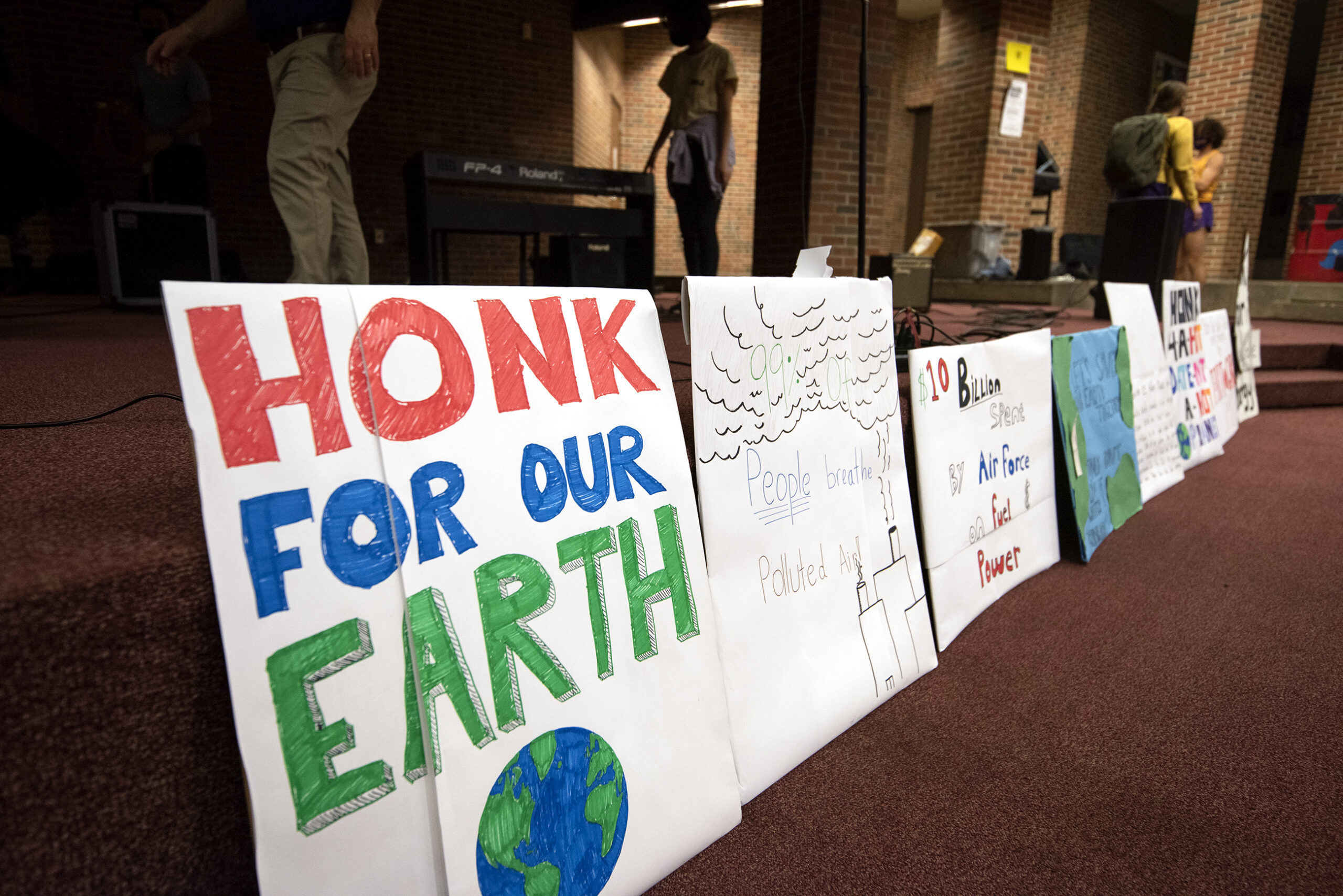 A sign that says "Honk for our Earth" is proper up against a stage.