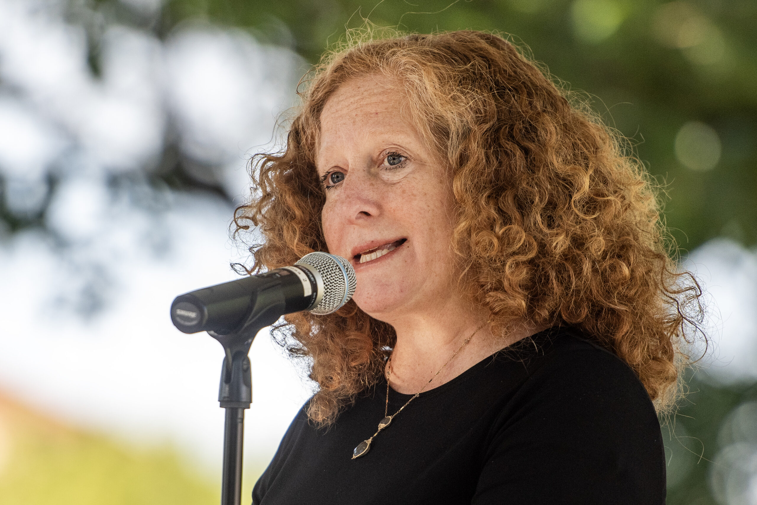 Chancellor Mnookin looks at the crowd as she speaks into a microphone at an outdoor ceremony.