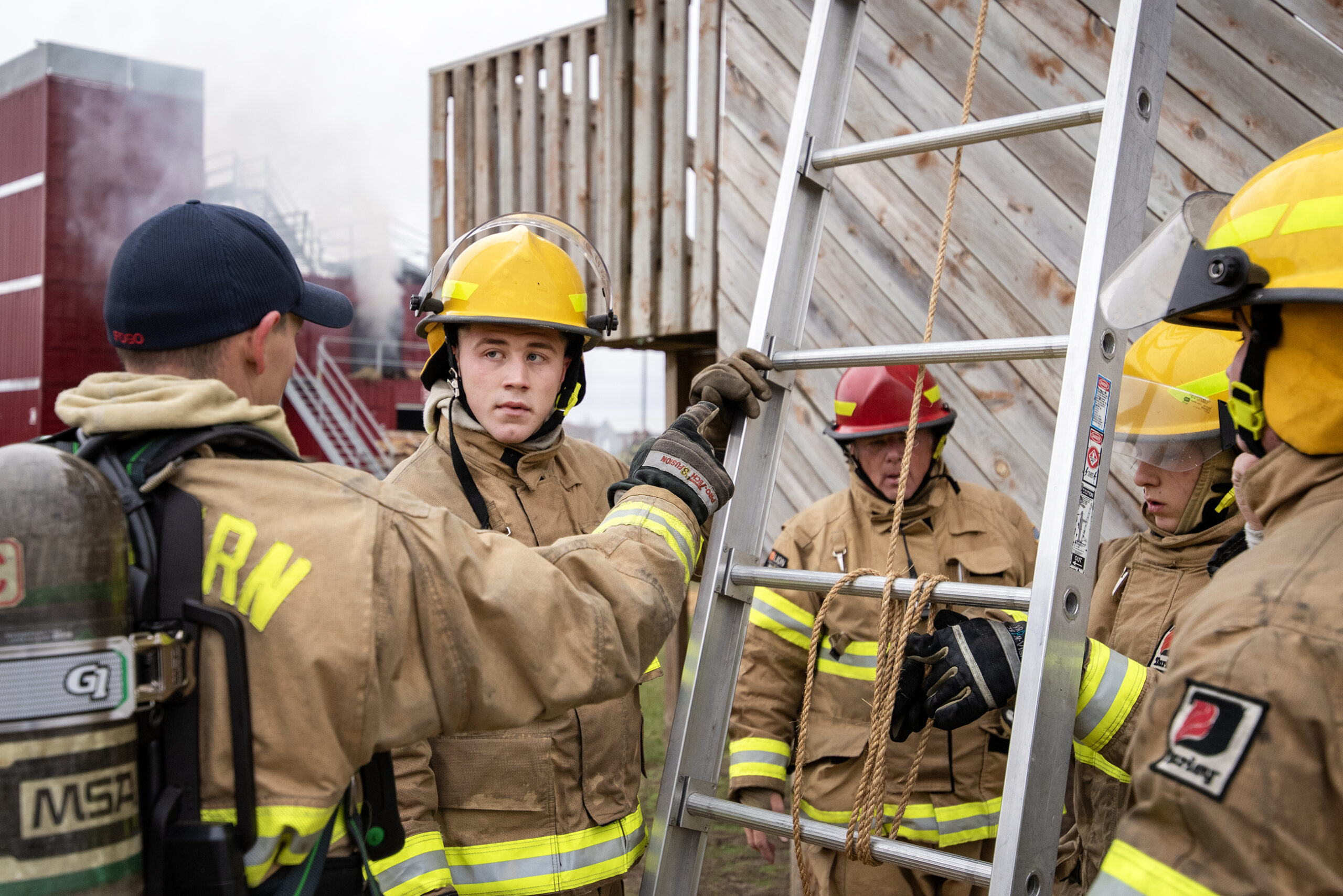 A student stands next to a ladder.