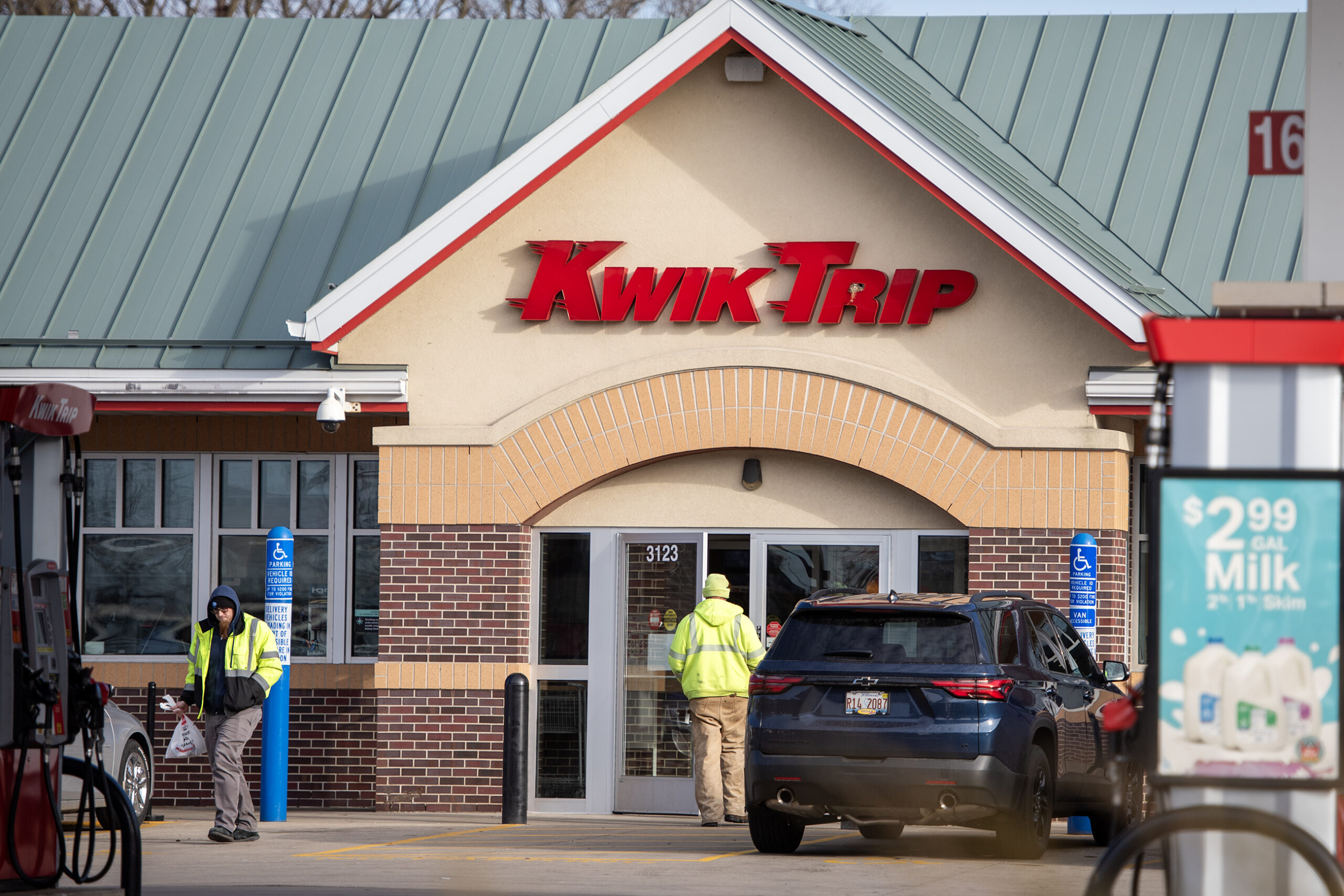 Customers enter and exit the front doors of a Kwik Trip convenience store on a sunny day.