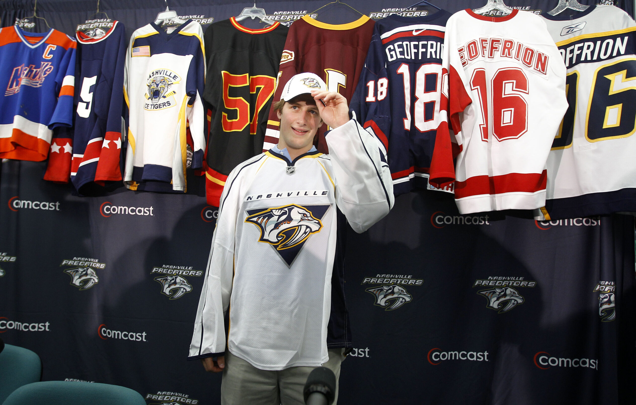 Blake Geoffrion poses in front of several of his previous jerseys after signing with the Nashville Predators