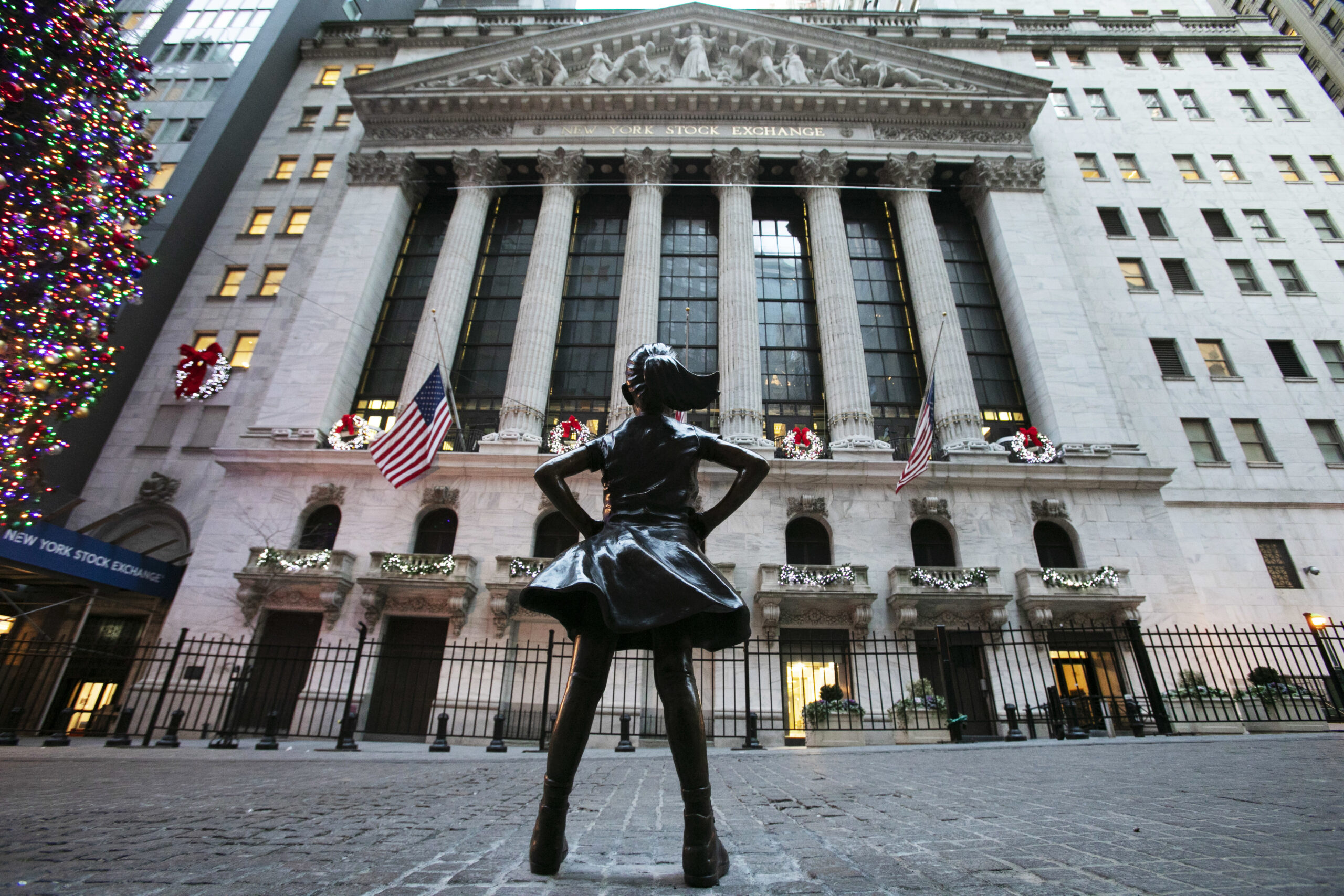 A statue of a girl defiantly looking at New York Stock Exchange building