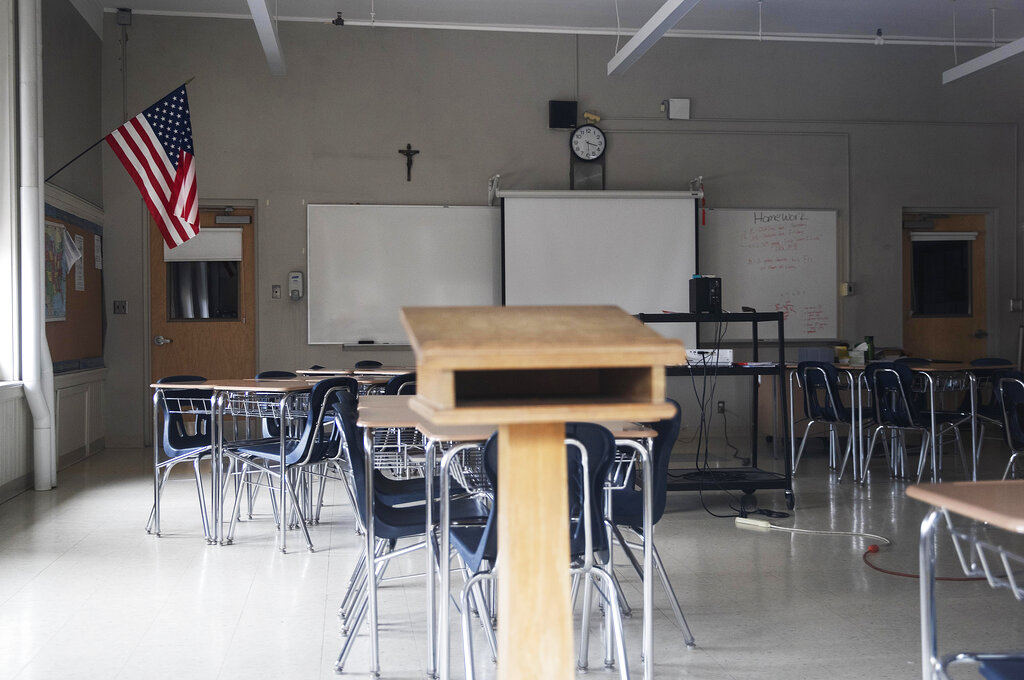This March 6, 2020, file photo, shows a classroom vacant through a window at Saint Raphael Academy in Pawtucket, R.I., as the school remains closed following a confirmed case of the coronavirus. (AP Photo/David Goldman, File)