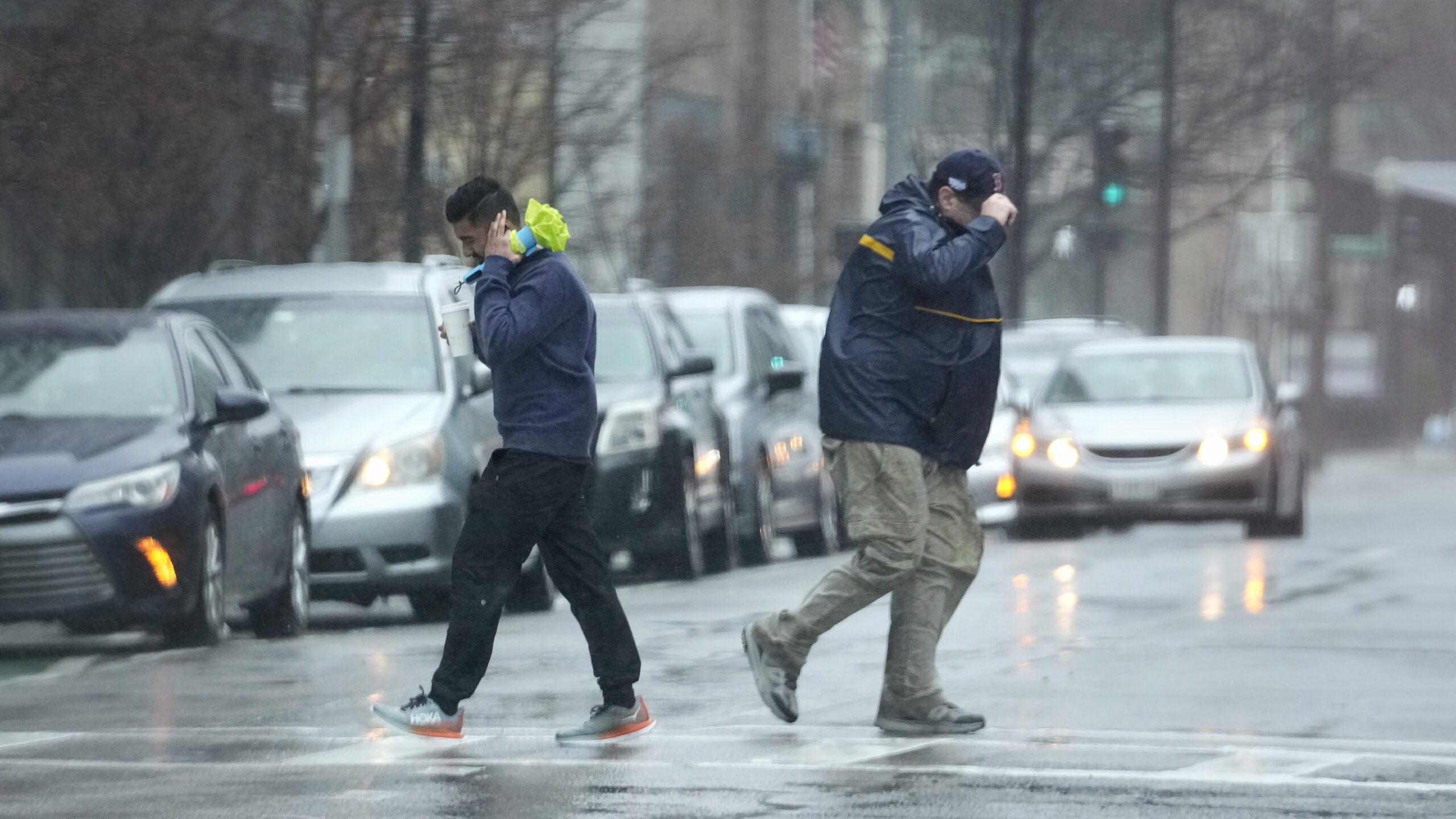 Pedestrians are buffeted by wind as they cross a street Monday in Boston.