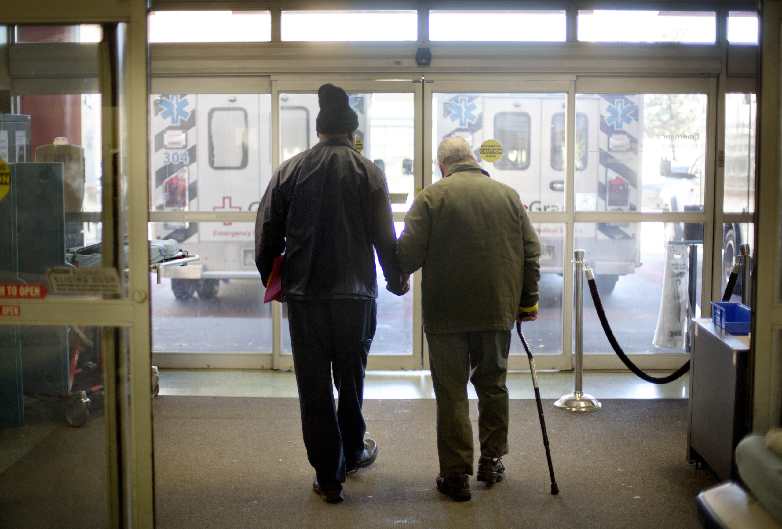 a patient at right is assisted while walking out of the emergency department at Grady Memorial Hospital, in Atlanta